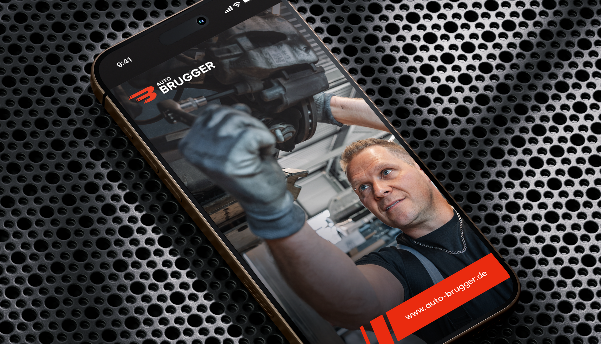 Mockup eines Social Media Beitrags der Firma Auto Brugger in einem Smartphone. Im Beitrag sieht man das Logo, die URL sowie das grafische Gestaltungselement des Unternehmens sowie einen Mann, der an der Unterseite eines Autos arbeitet, das auf einer Hebebühne steht.
