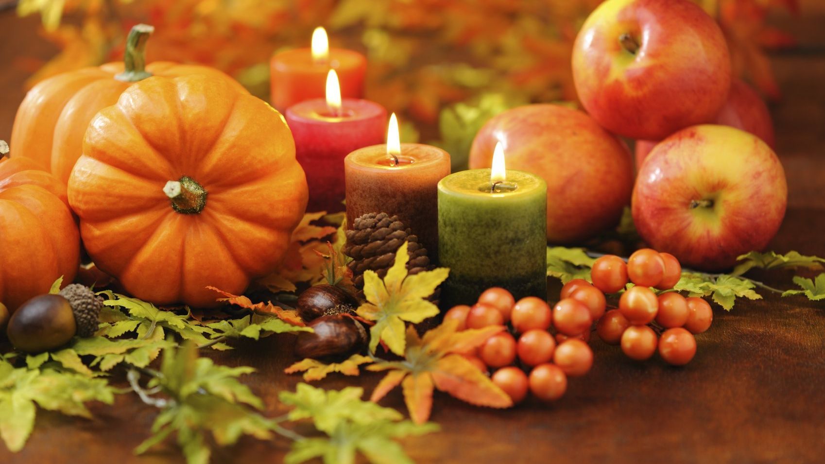 Link zur Seite Erntedank Das Symbolbild zum Erntedankfest zeigt Kerzen, Kürbisse, Äpfel und Kastanien.