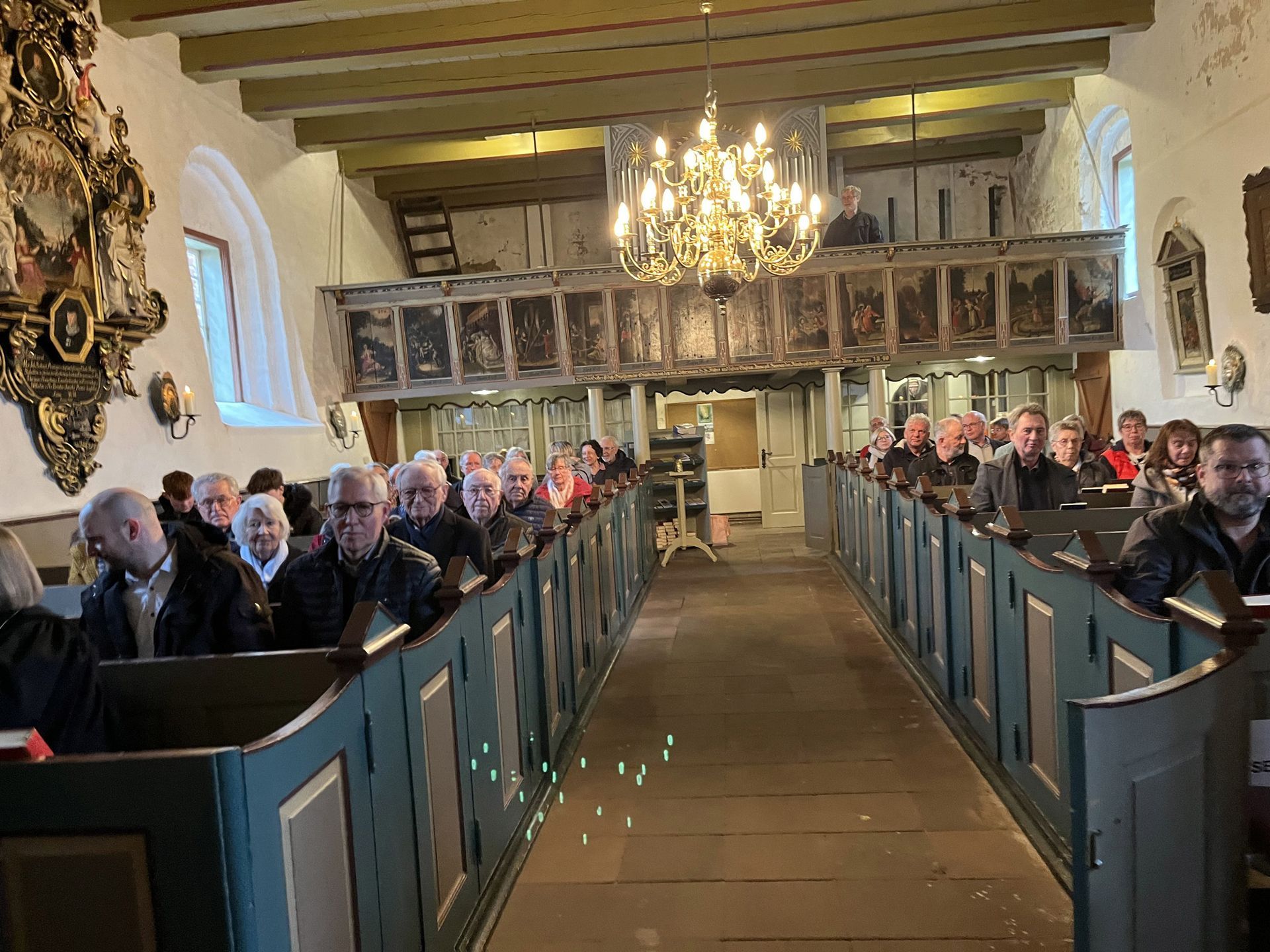Das Bild zeigt die Gemeinde beim Festgottesdienst. Die Gemeindemitglieder sitzen auf den Bänken und warten auf die Ansprache