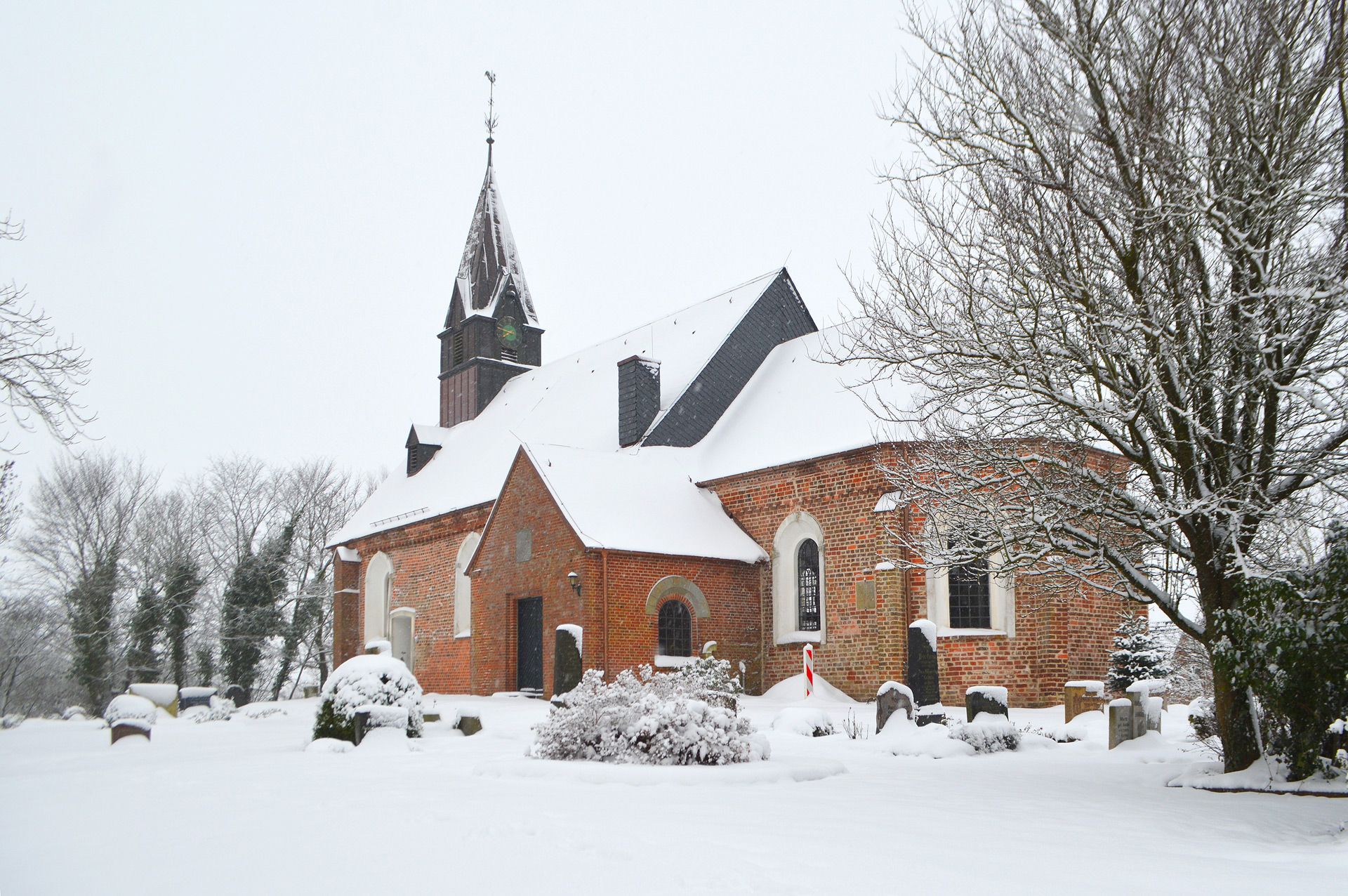Das Bild zeigt die verschneite Kirche St. Johannis in Poppenbüll im Winter