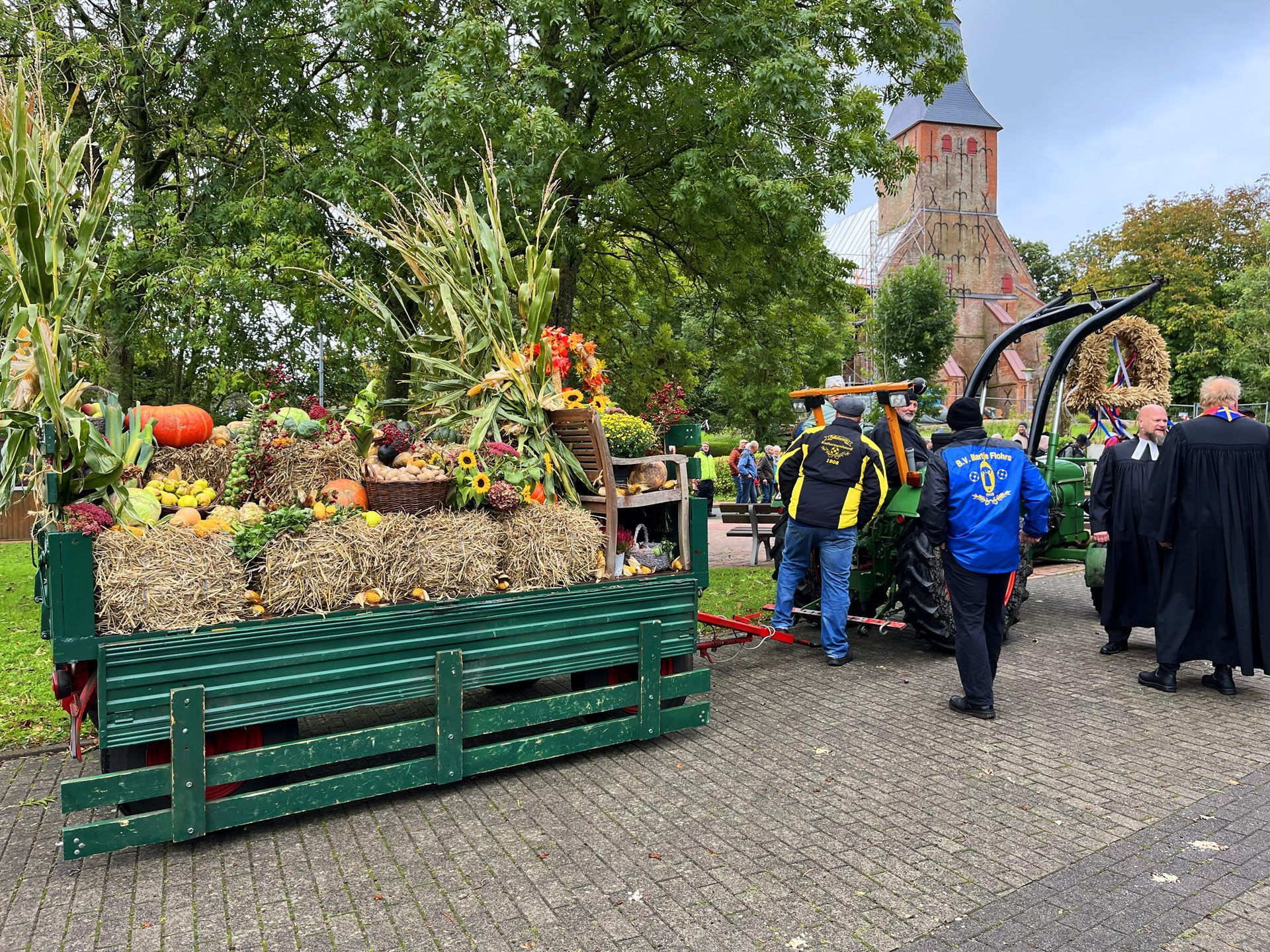 Erntedankfest. Umzugswagen, rechts im Bild die Kirche St. Anna, Tetenbüll.
