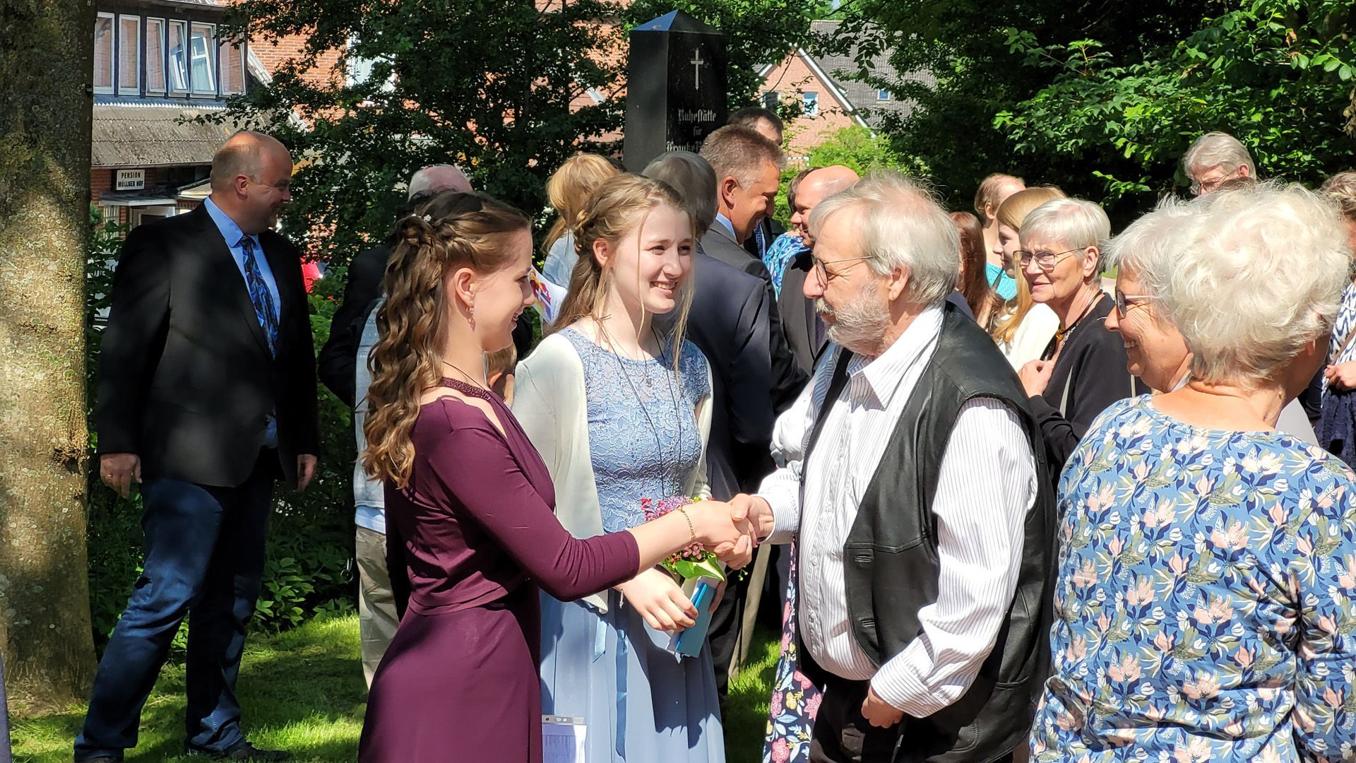 Das Bild zeigt die Konfirmanden beim Händeschütteln vor der Kirche.
