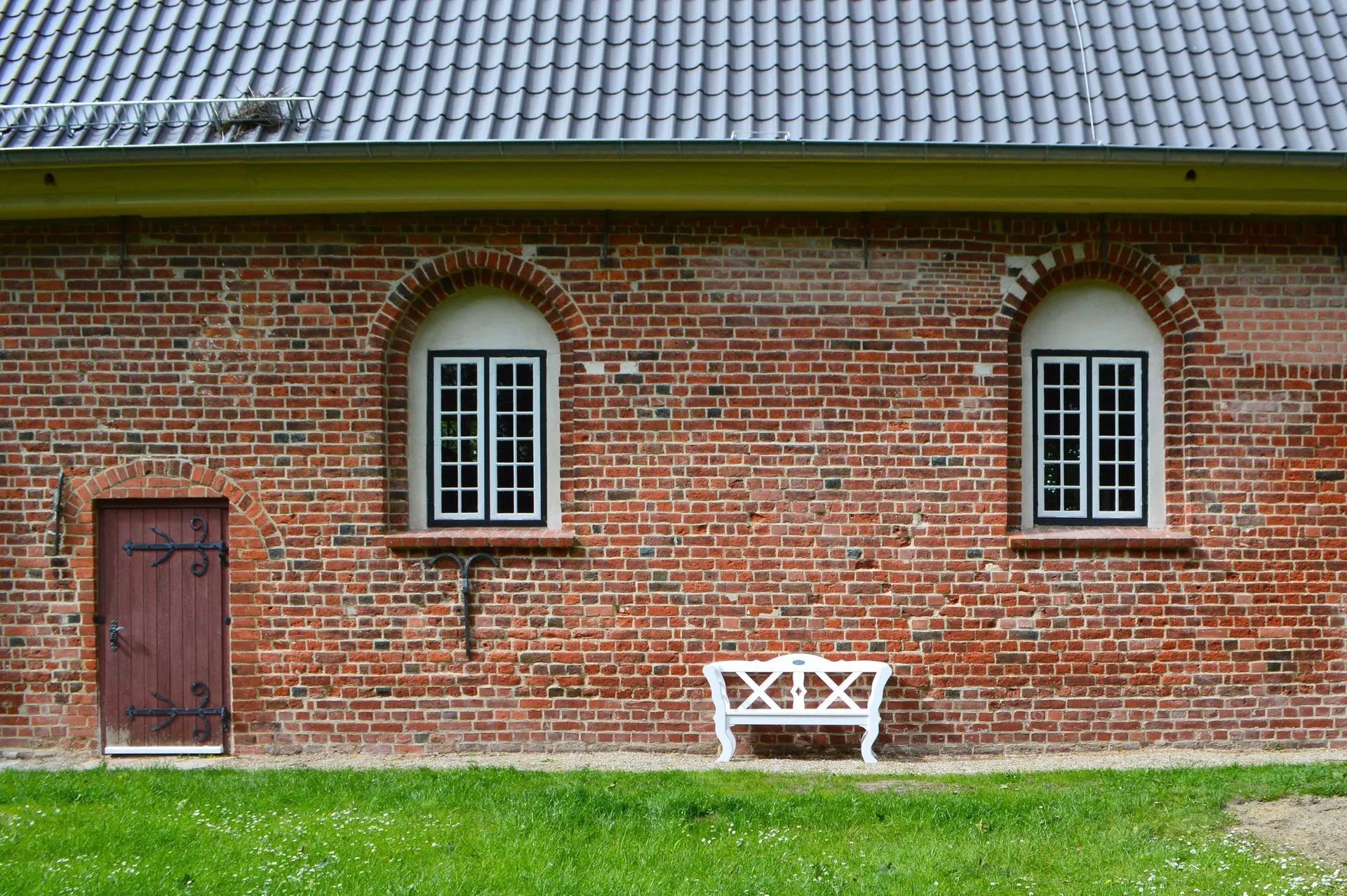 Das Bild zeigt die sanierte Südfassade mit einer weißen Bank zum Ausruhen.