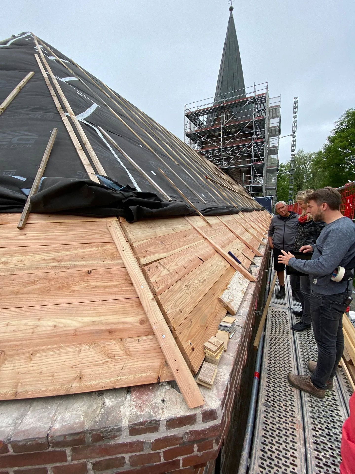 Baubesprechung auf dem Gerpüst bei Dach-Sanierungsarbeiten