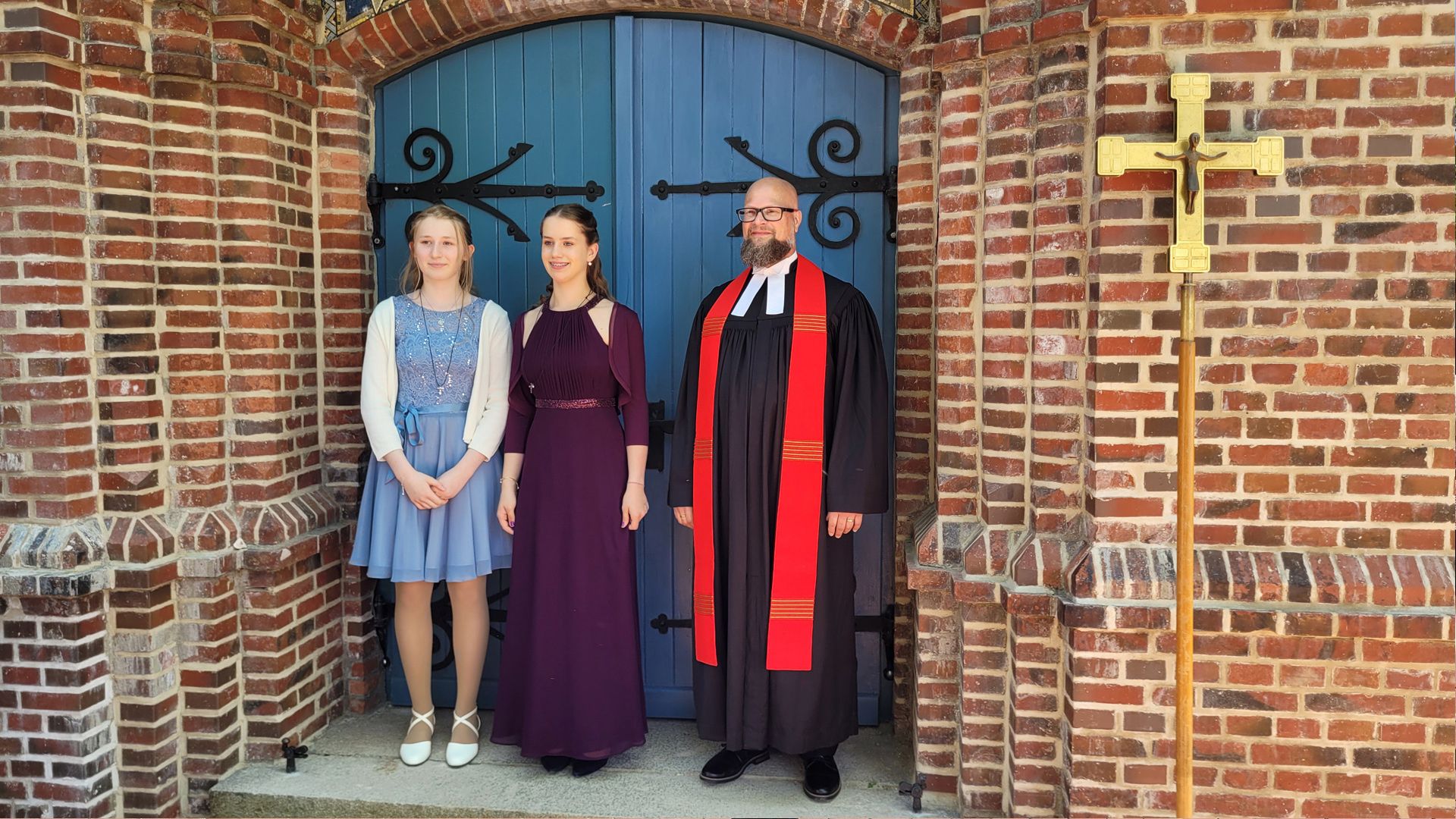 2 Konfirmanden mit Pastor Reglinski vor dem Haupteingang der Kirche St. Michael