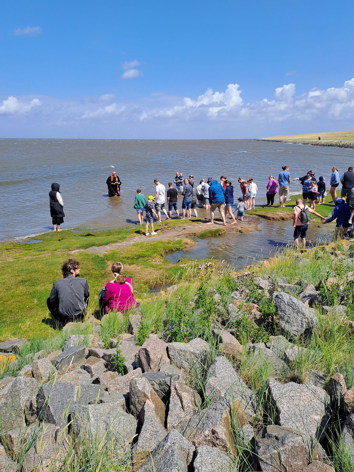 Das Bild zeigt die Deichtaufe in Stufhusen in Westerhever mit Pastor Knippenberg. Der Pastor steht im Nordseewasser.
