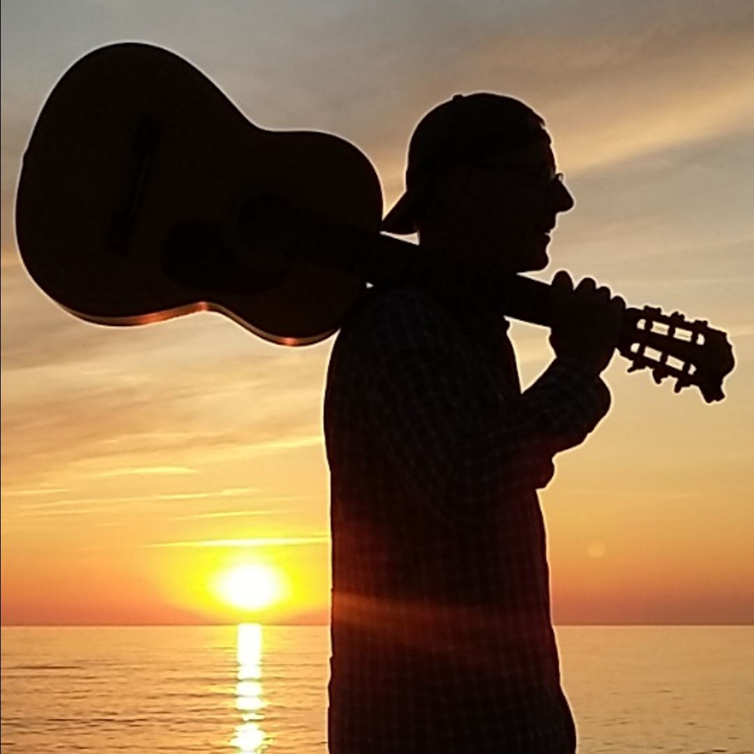 Foto: S. Godglück Ralf Godglueck mit Gitarre am Strand zum Sonnenuntergeng