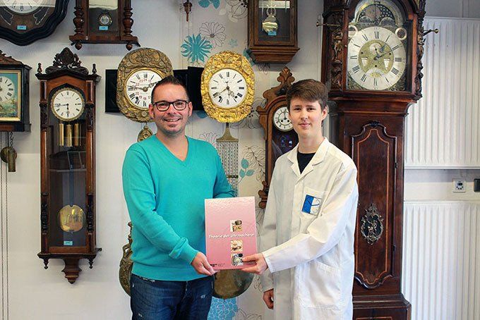 Timo Boxberg überreicht dem angehenden Uhrmacher Herr Ziemer das Fachbuch Timo Boxberg