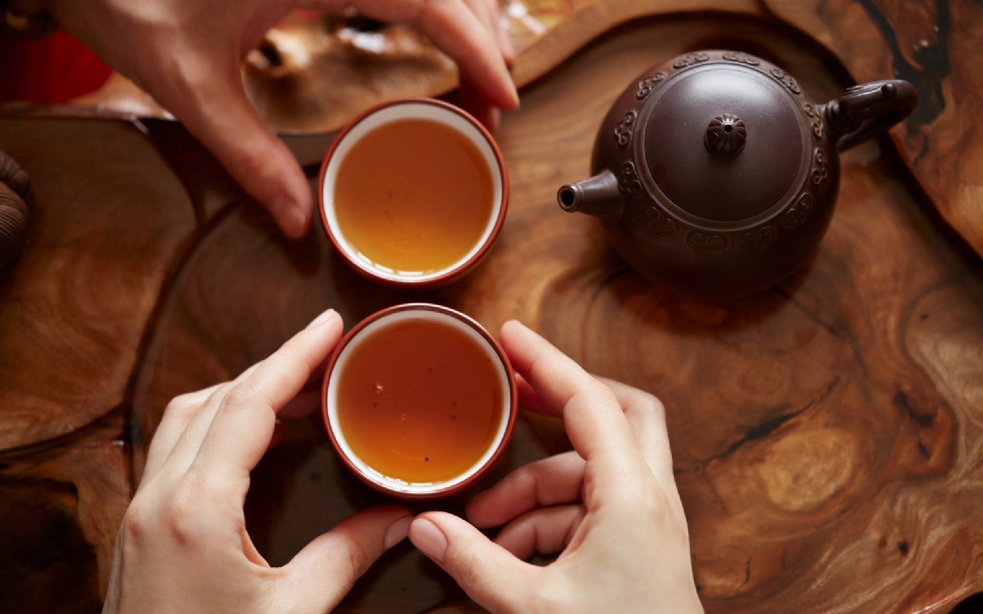 hands holding warm cups of tea
