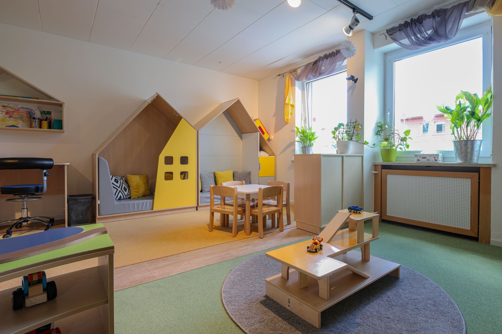 Zu sehen ist ein Innenfoto der Einrichtung mit Tisch, Spielmöglichkeiten und Kuschelecke.