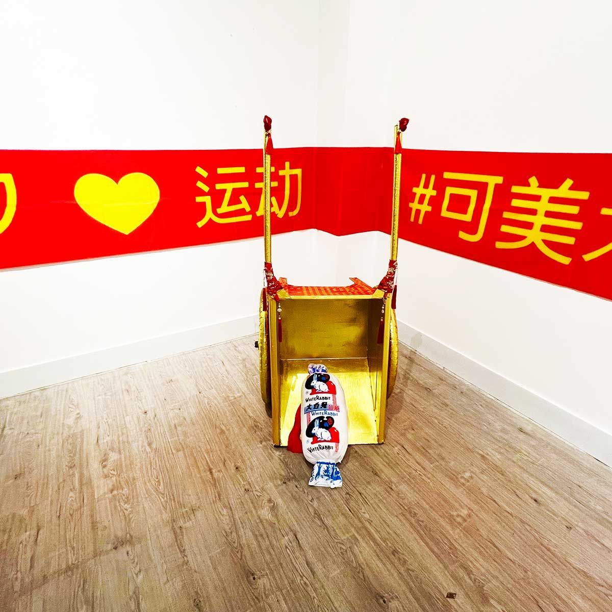 Installation réalisée in situ au Ke Art Museum de Shanghai.
Banderolle en tissu imprimé jaune sur rouge, brouette tapissée de fil or et de broderie de prières rouge, passementeries chinoise, coussin en forme de bonbon White Rabbit, led vilolette
dimensions variables, 2025