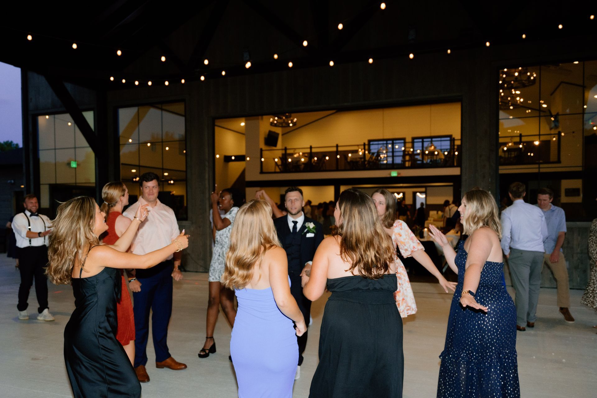 Guests on the outdoor wedding dance floor on the covered back porch at Union 12, a Fort Wayne wedding venue, providing a perfect space for dancing outside