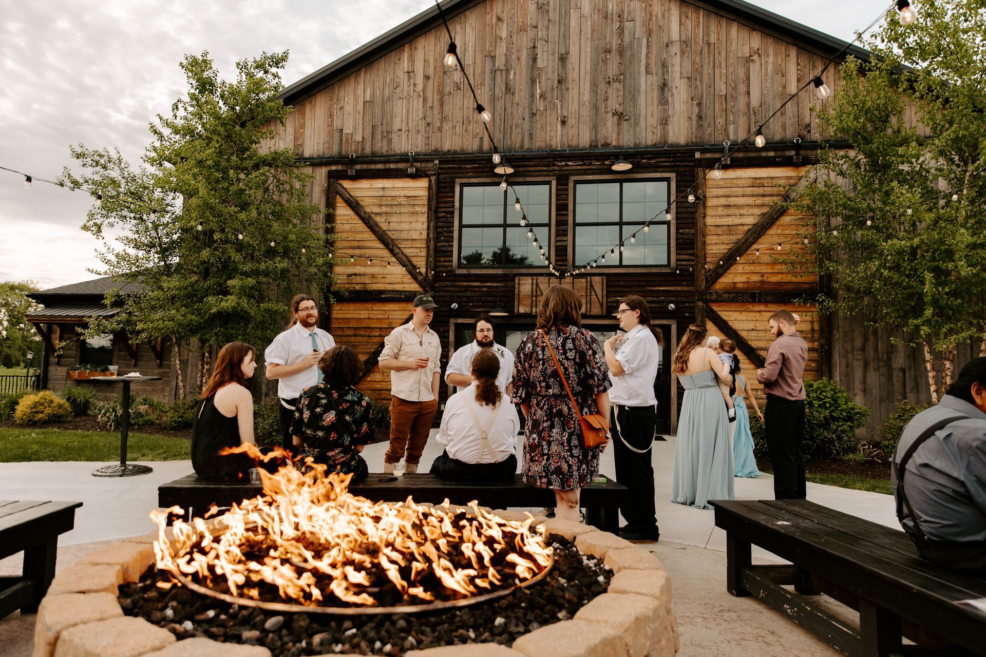 Guests enjoying cocktail hour by the fire pit at Union 12, with the front of the venue in the background, creating a warm and inviting atmosphere for a wedding celebration.