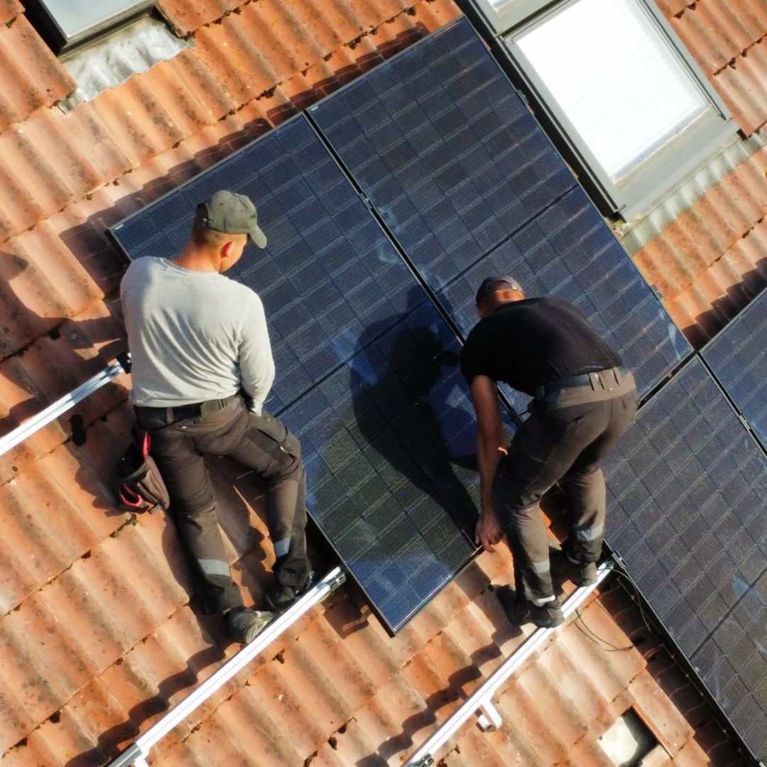 ENKO Solutions GmbH Mitarbeiter verbauen die Solarpaneele auf einem Satteldach.