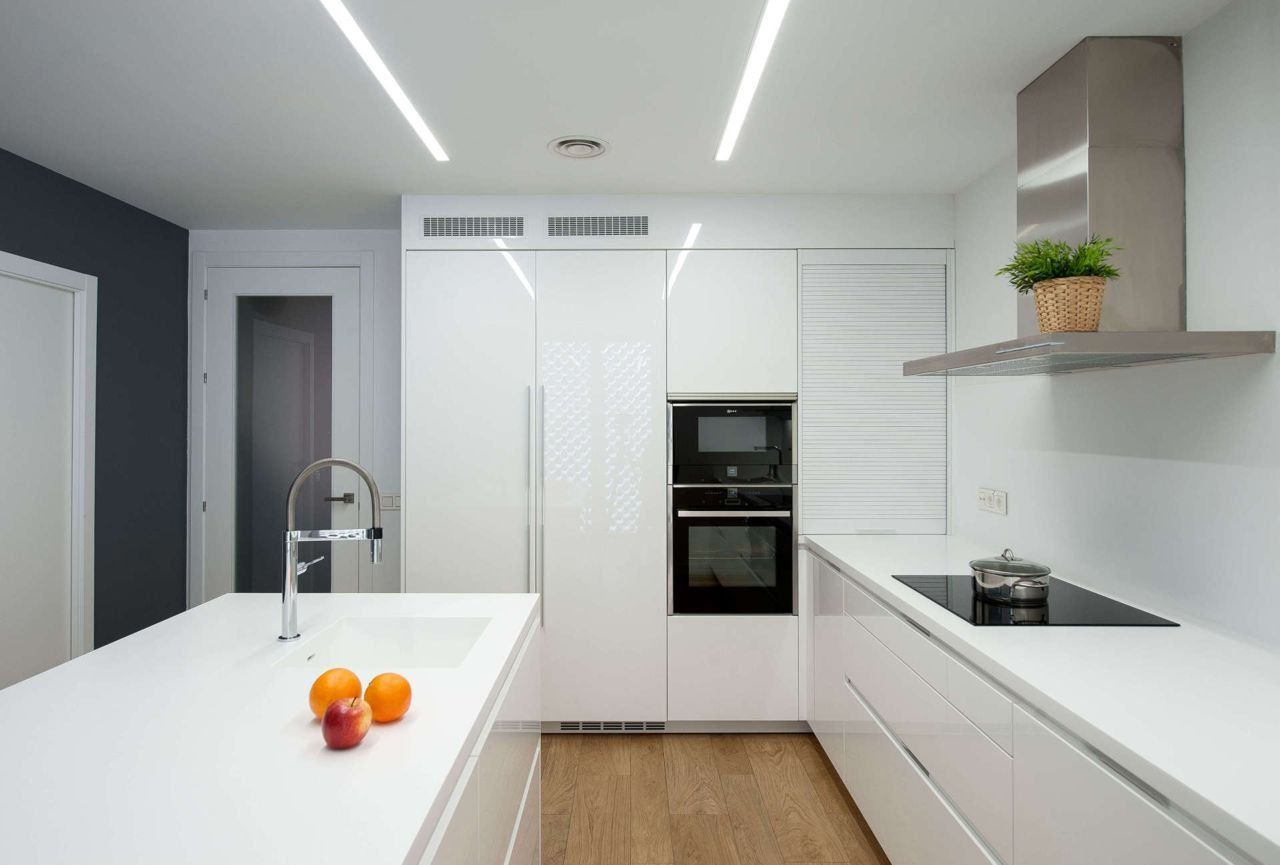cocina blanca de diseño con encimera en blanco y campana de acero