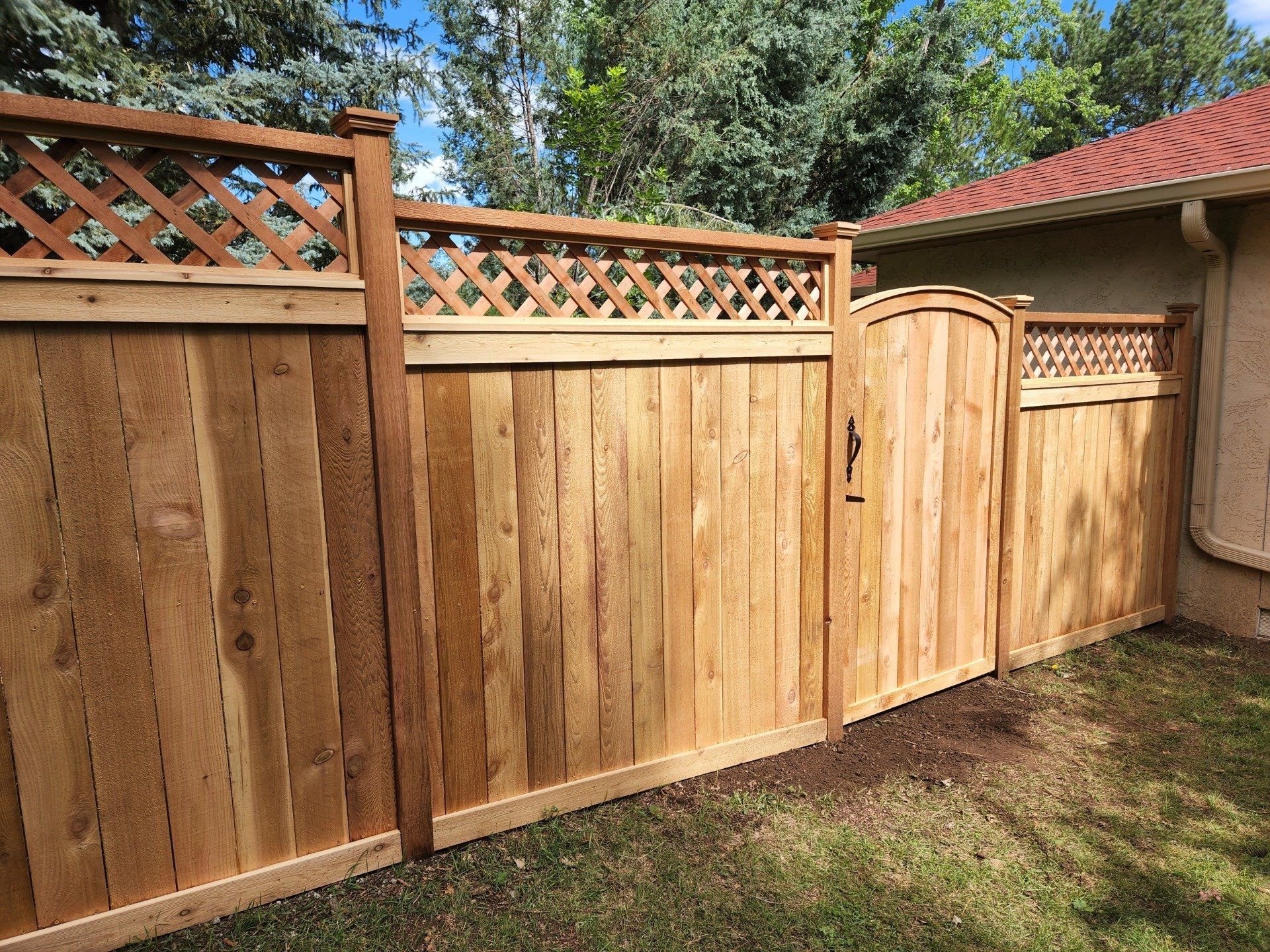 Lattice-top craftsman-style privacy fence and curved-top gate.