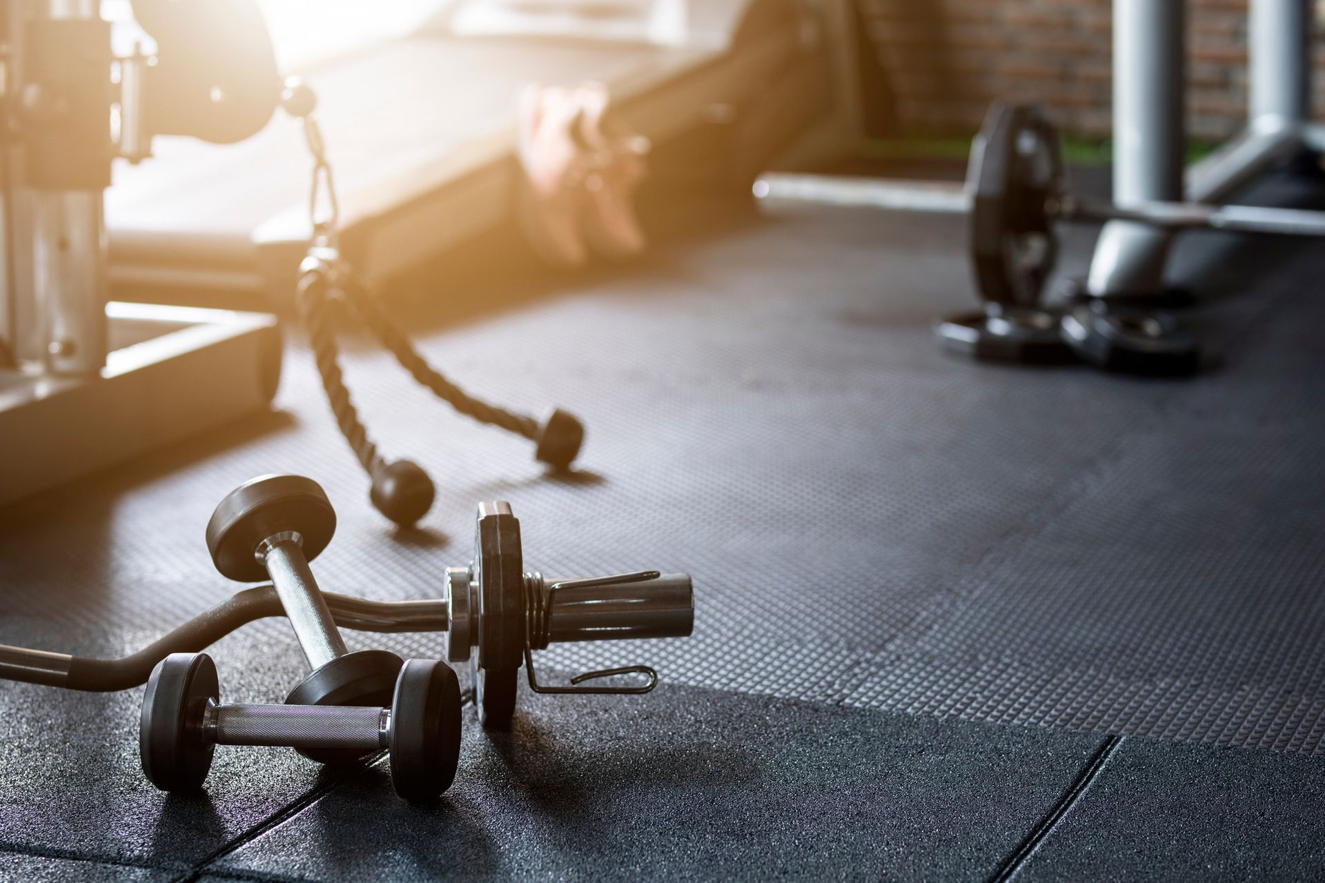 Hanteln auf einem Fitnessraumboden mit Trainingsgeräten und auch gereinigtes Fitnessstudio durch unseren Reinigungsprofi