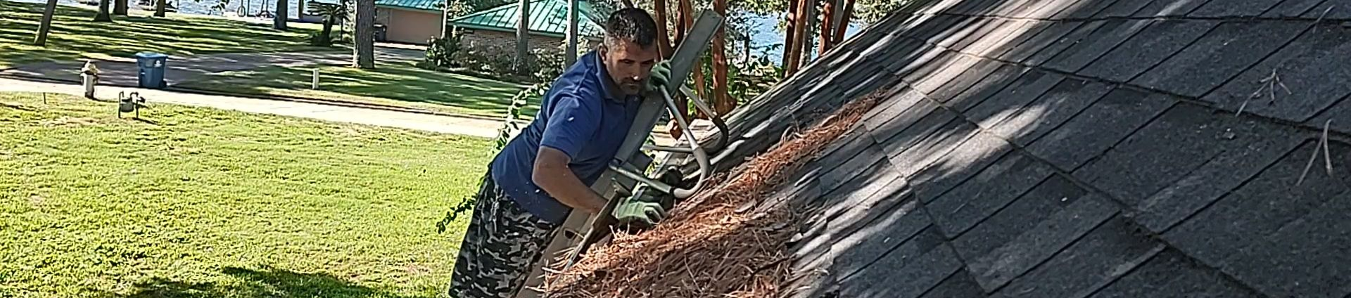 Clogged gutter maintenance in Magnolia, Texas; specialist clearing pine needle debris to prevent water damage.
