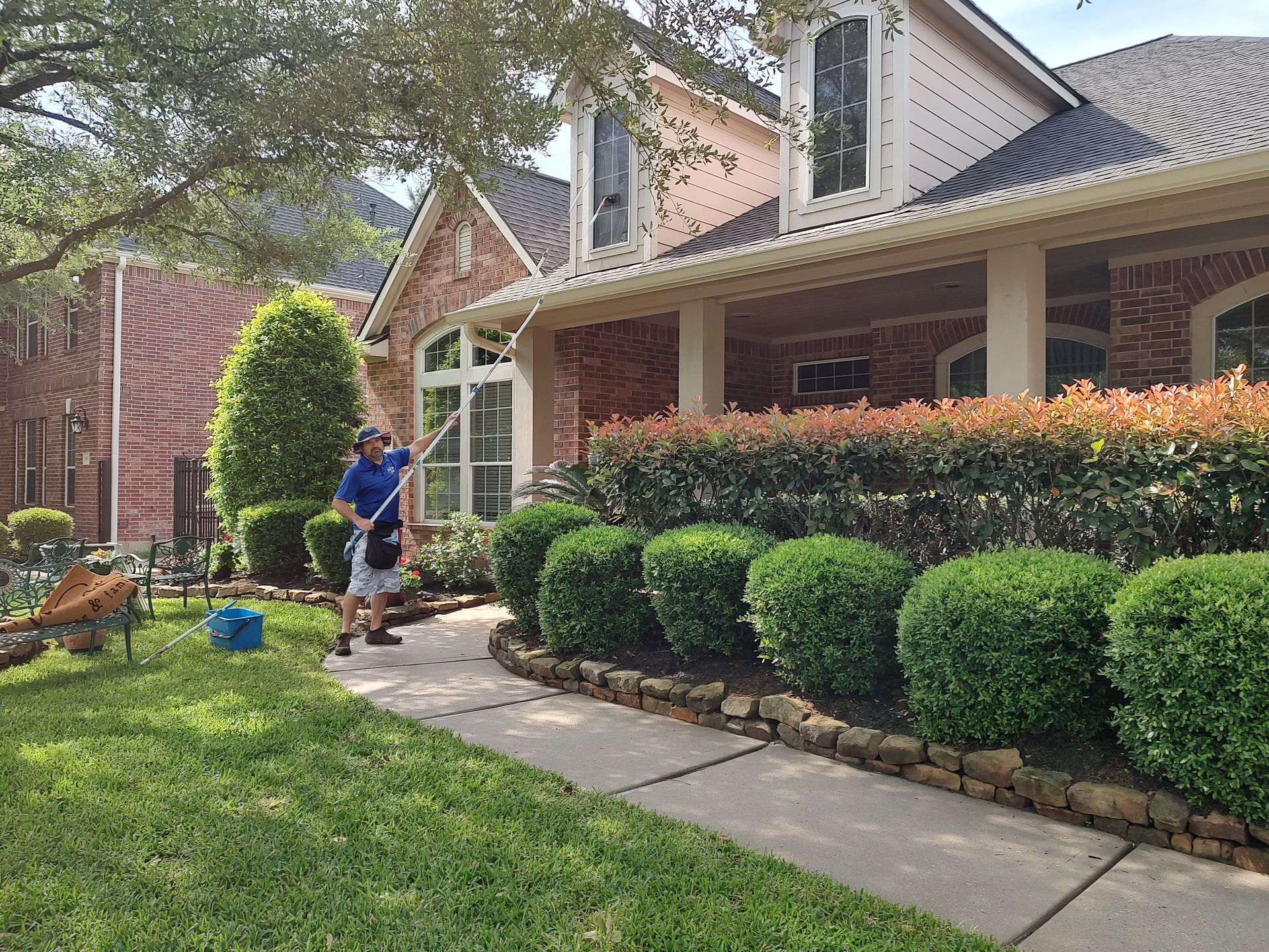All Git Out Services technician using a professional window cleaning pole on a second-story dormer in Magnolia, Texas.