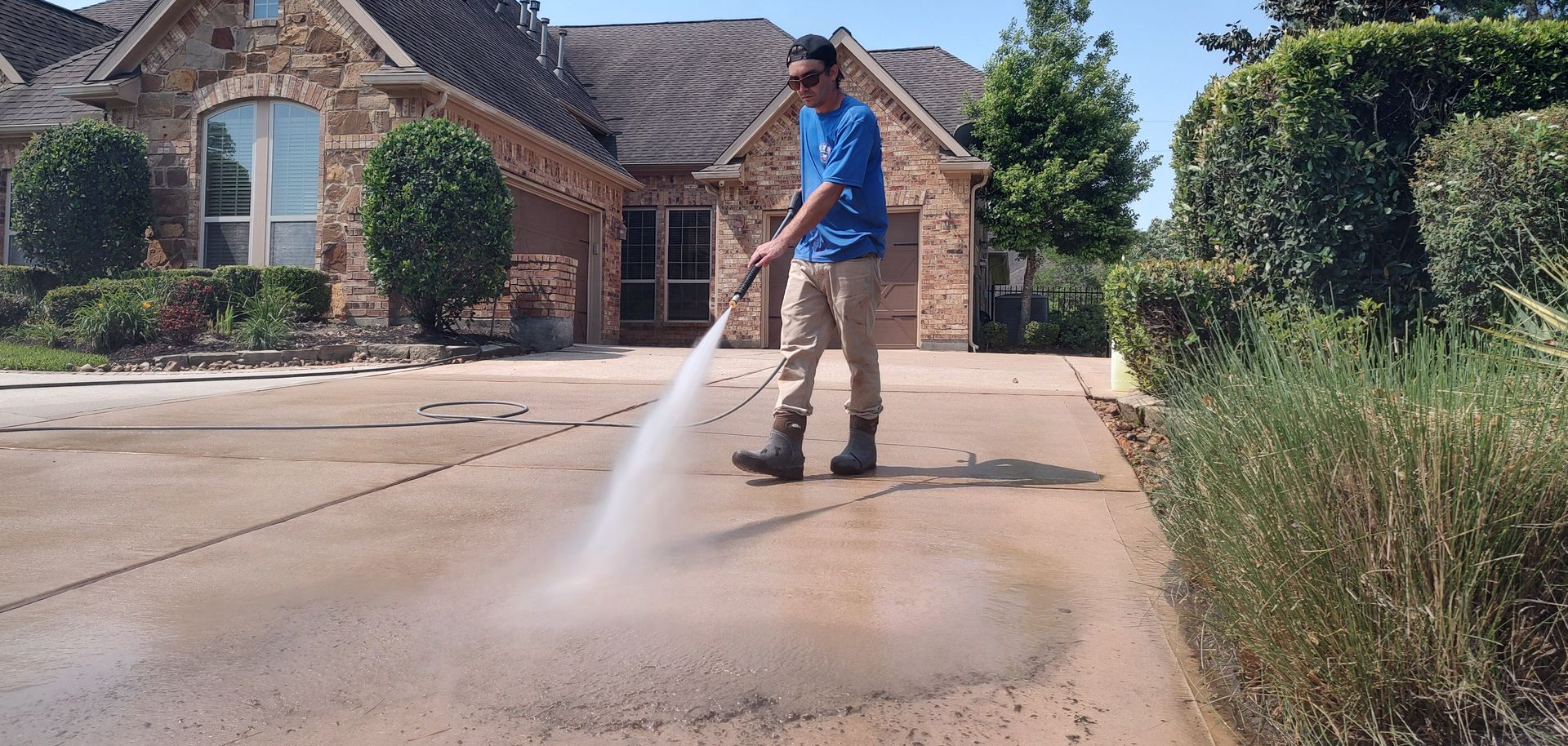 Rinsing the algae off a driveway after pressure washing in Magnolia Texas