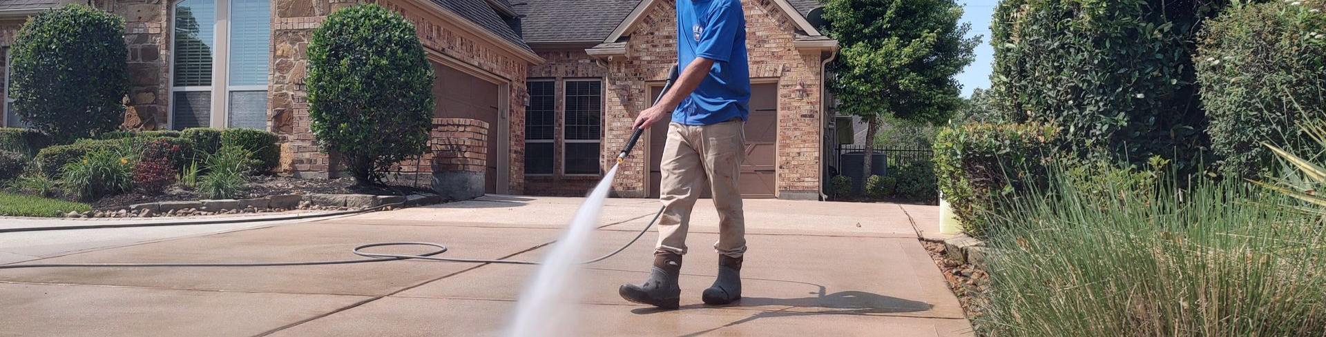 Rinsing the algae off a driveway after pressure washing in Magnolia Texas