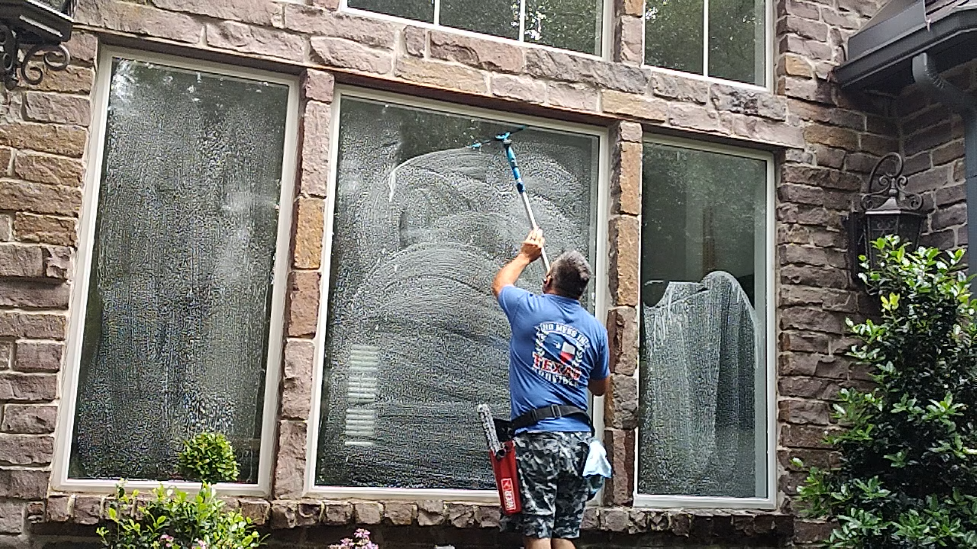 window cleaning specialist using a professional squeegee to remove water from residential glass.
