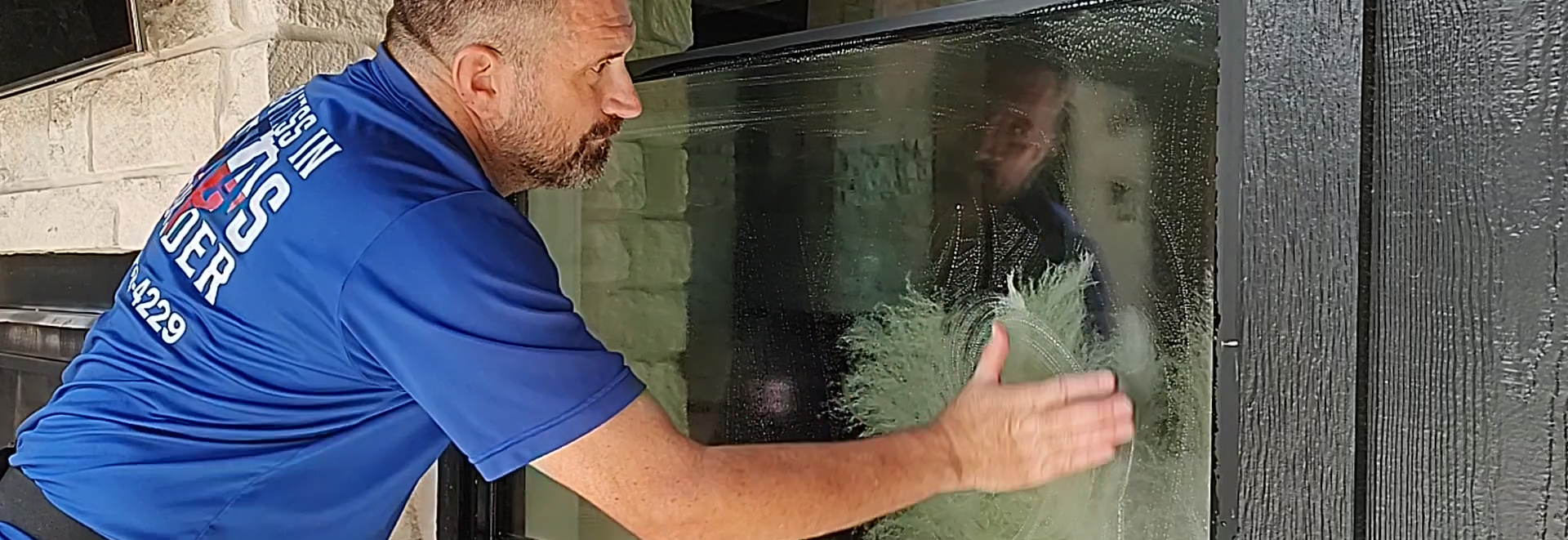 Hand-scrubbing a window pane with ultra-fine quad-zero (0000) steel wool to safely remove baked-on construction gunk, paint splatters, and tree sap from residential glass.