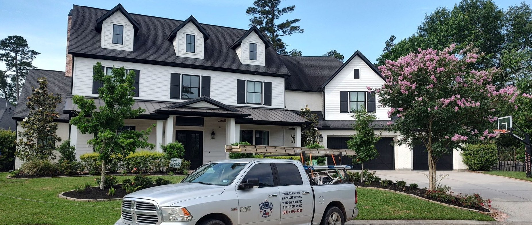 A professional truck from All Git Out Services parked in front of a beautiful home with meticulously cleaned windows in Magnolia, Texas.