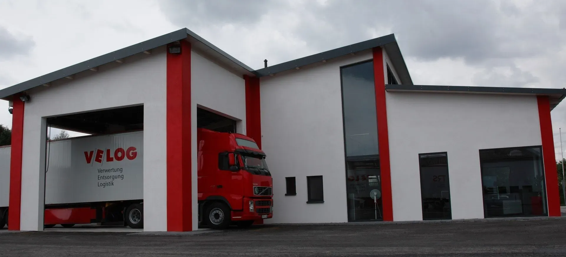 Das VELOG Bürogebäude mit einem LKW der durch die Werkstatt fährt