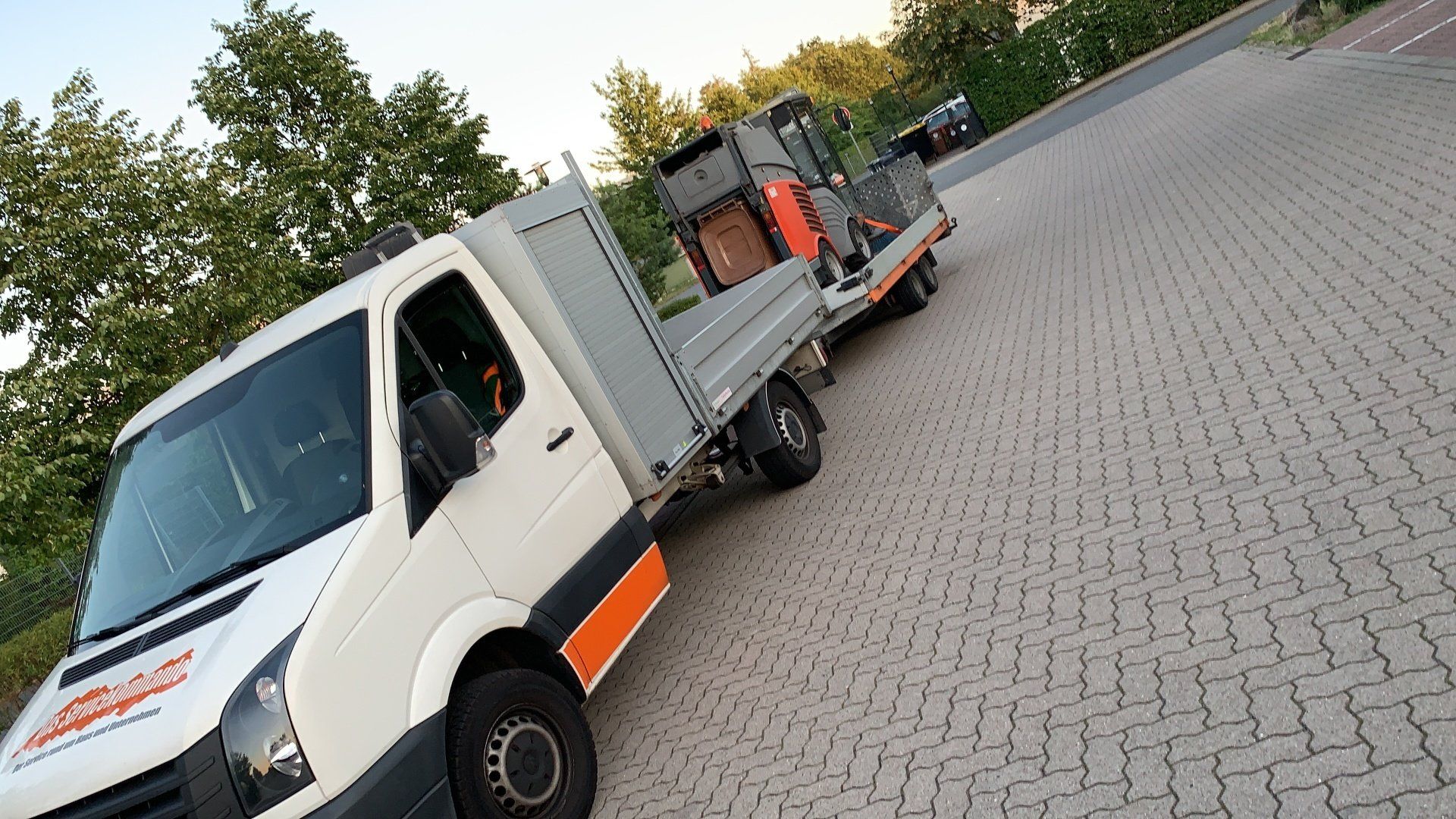 Hausmeister mit Fahrzeug und Kehrmaschine