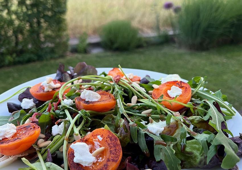 Ein Teller mit grünem Salat getoppt mit Obst, Schafskäse und Gemüsestücken