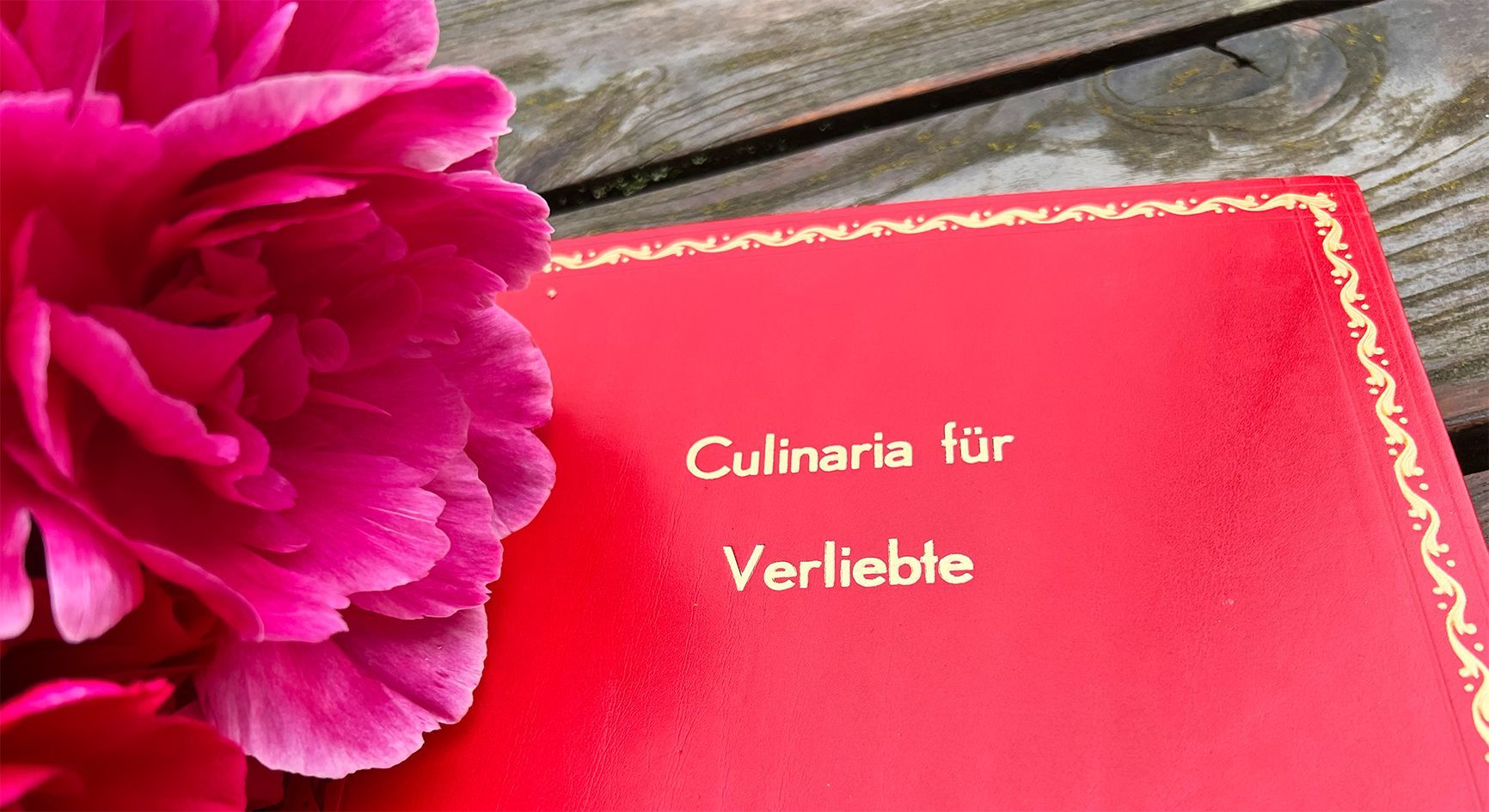 Brautstrauß aus Pfingstrosen auf Buch mit roten Einband mit der Aufschrift Culinaria für Verliebte