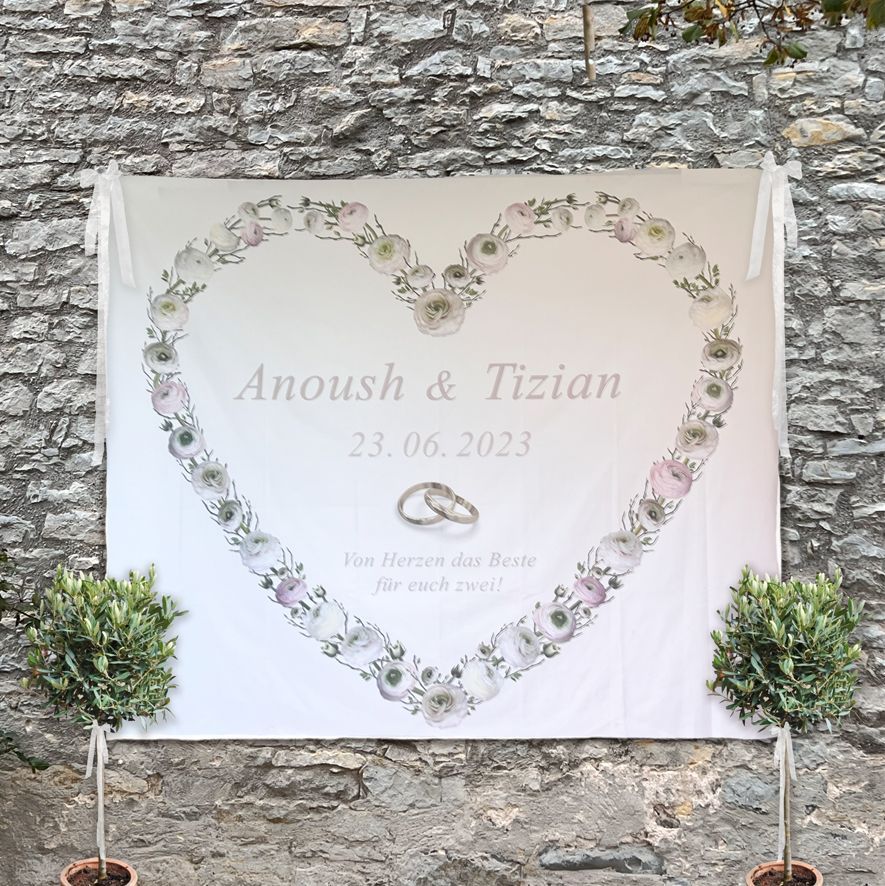 Man sieht ein Tuch auf dem ein Herz aus Blumen aufgedruckt ist sowie die Vornamen eines Brautpaares
