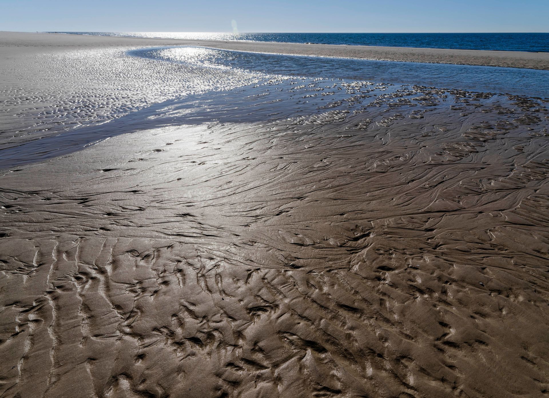Nasser Sand am Strand bei Gegenlicht Strand mit Wasser im Sandbereich im Gegenlicht