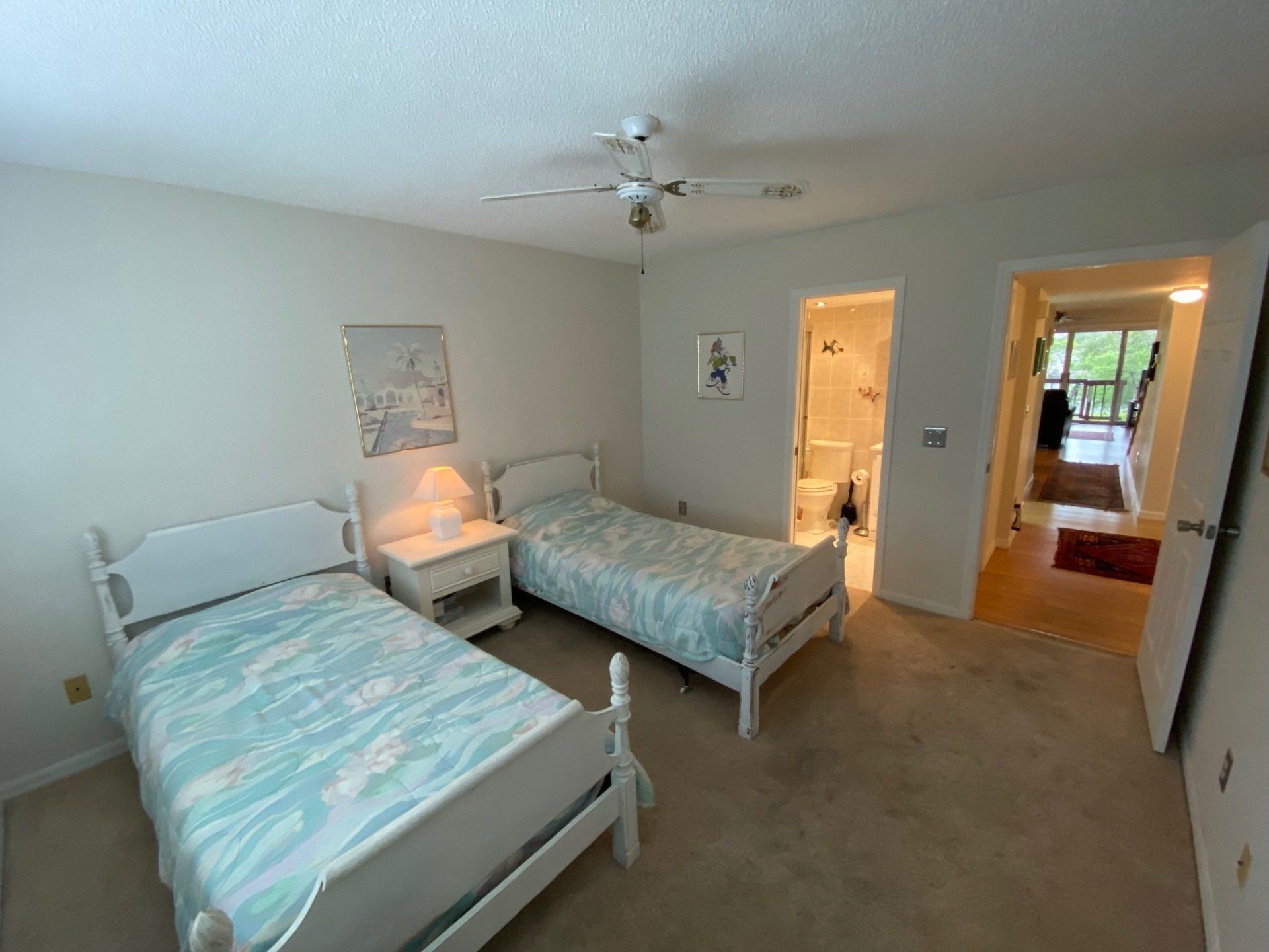 2 twin beds, white frames, blue bed covers, side table with lamp, beige carpet