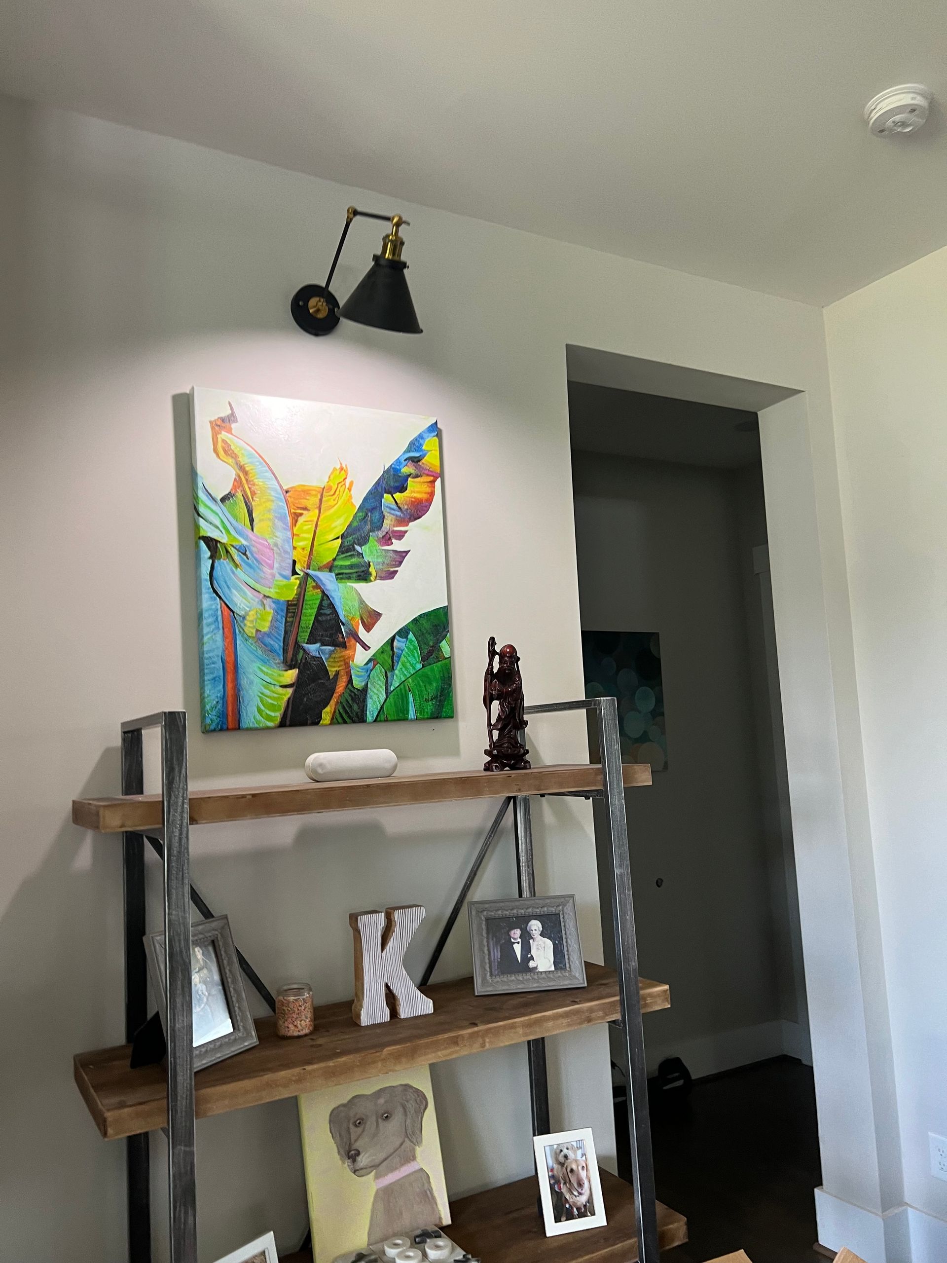 Custom wall sconce installation above built-in shelving in living room with modern tropical decor – Wake Forest, NC