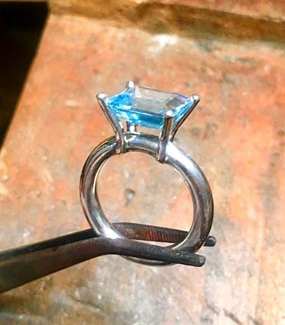 Sterling silver ring set with an emerald cut blue topaz stone in a chunky claw mount.
