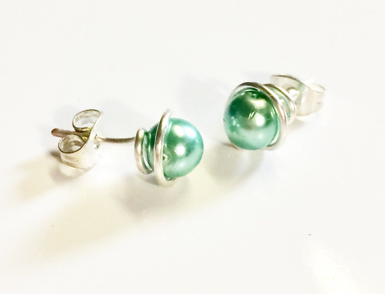 Various coloured swarovski glass pearls wrapped in plated wire to form a stud earring.