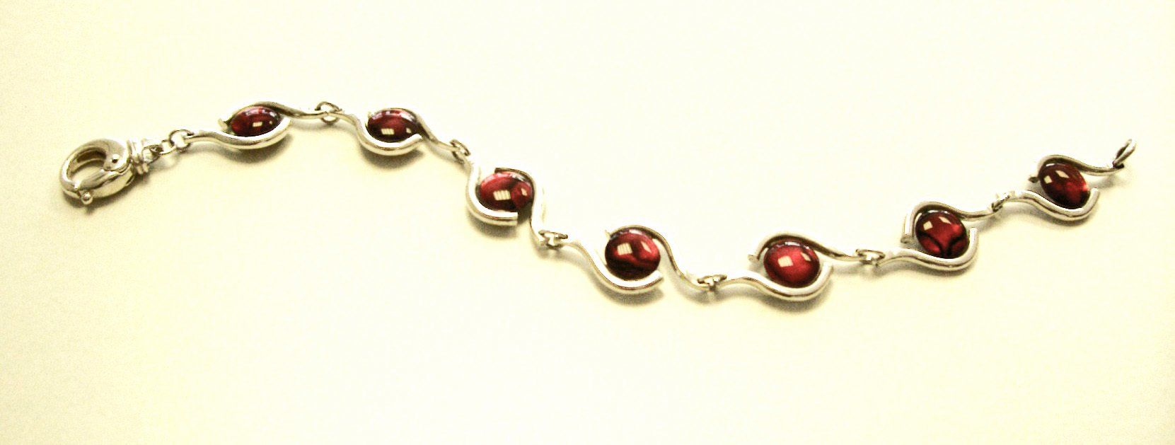 Sterling silver bracelet set with dyed red paua shell cabochons. Fastens with a round lobster catch.