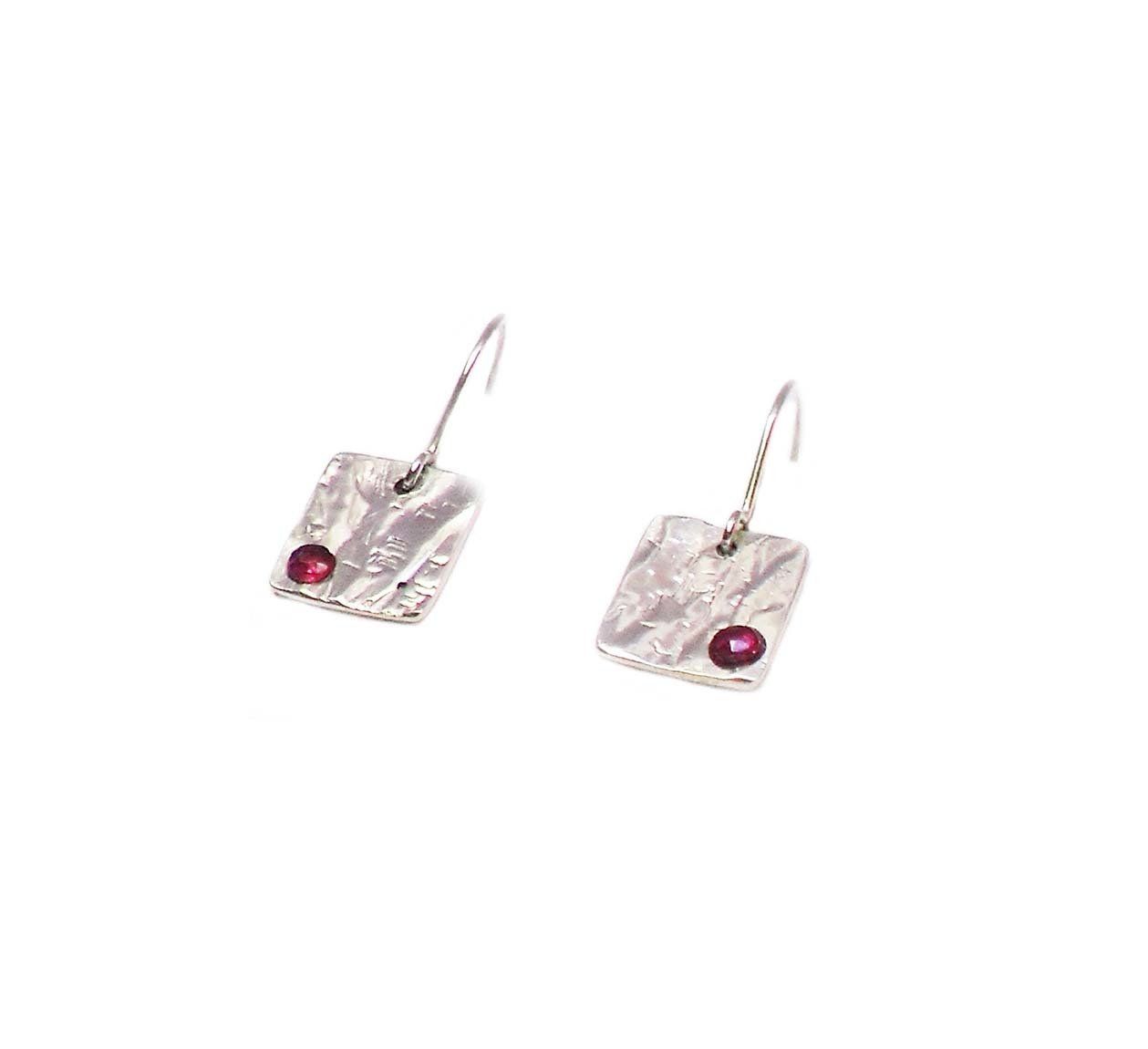 Small square hammered effect sterling silver drop earrings set with small round ruby stones.