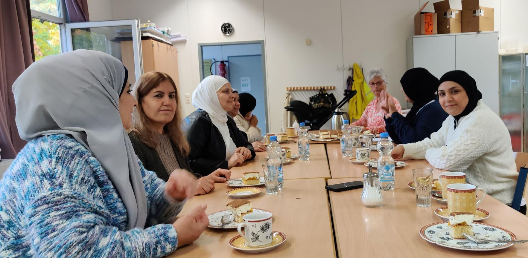 Frauen, Mitglieder des Vereins, sind an einem Tisch mit Kaffee und Kuchen und unterhalten sich.
