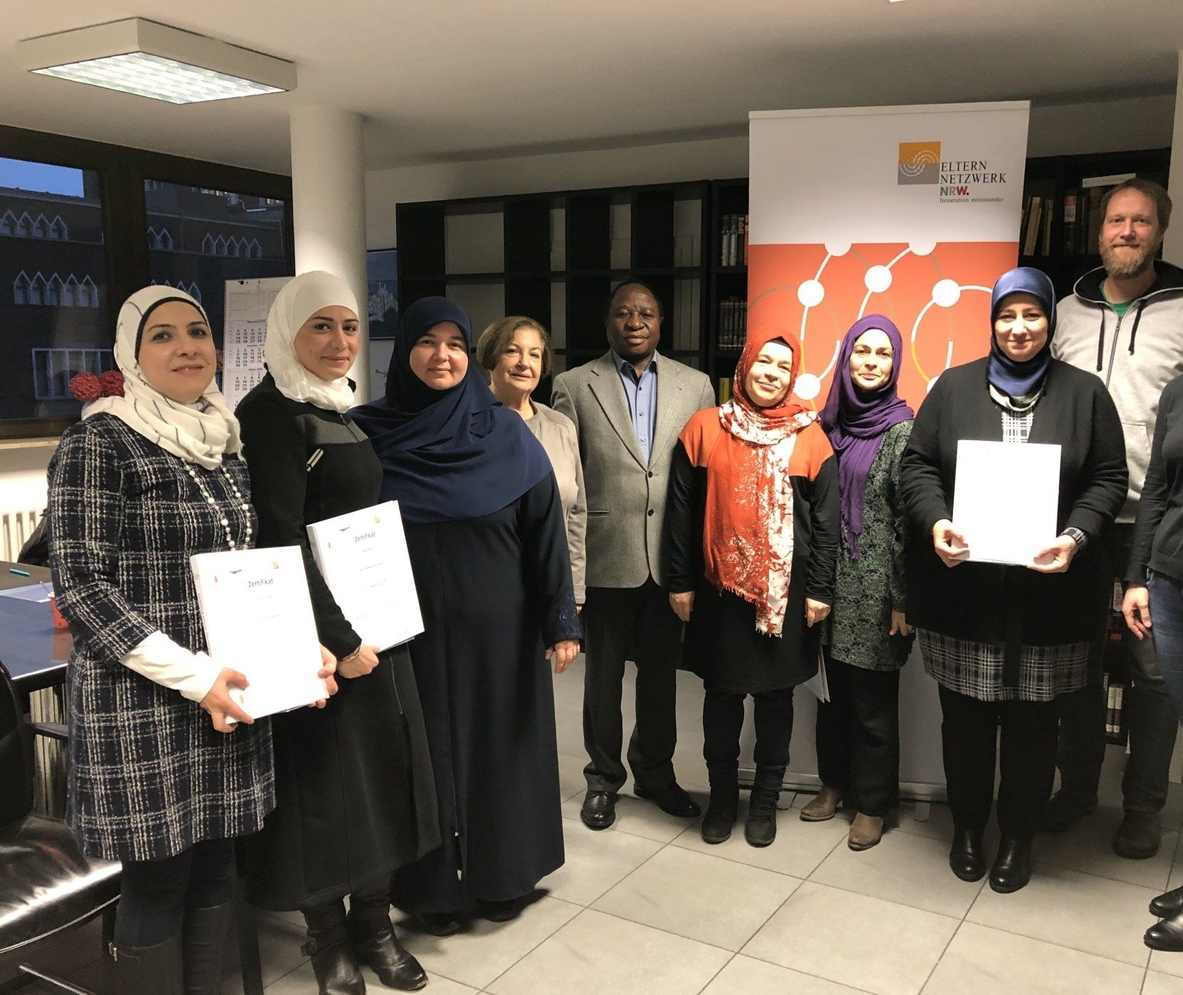 Mehrere stolze Eltern mit ihren Zertifikaten im Gruppenbild. Link führt zu Projektseite Eltern-Familien-Netzwerk