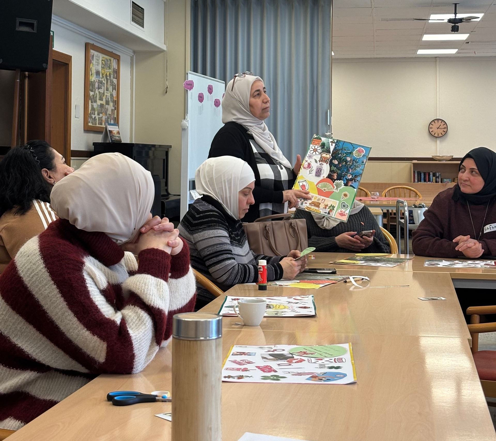 Gruppentisch von Frauen, bei der eine Teilnehmerin ihr Vision-Board vorstellt.