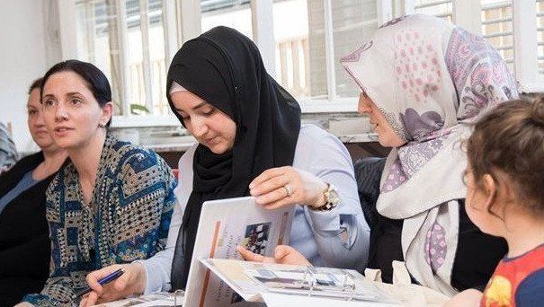 Junge Frauen mit Kopftuch über Informationsmaterial. Link führt zu Projektseite Your Voice, Your Choice