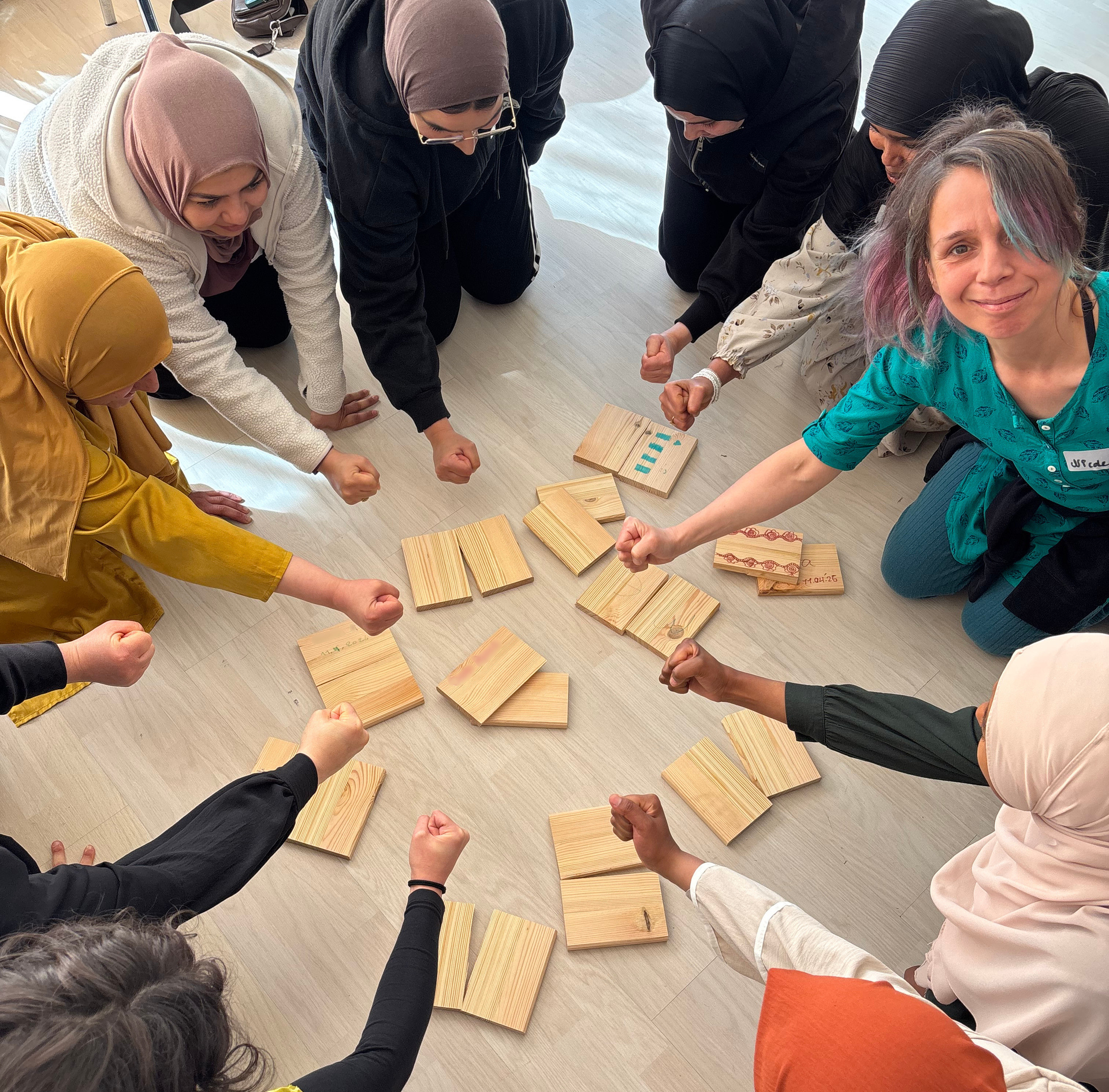 Frauen beim WenDo Kurs im Kreis, vor ihnen zerschlagene Holzstücke als Selbstverteidigungs-Übung.