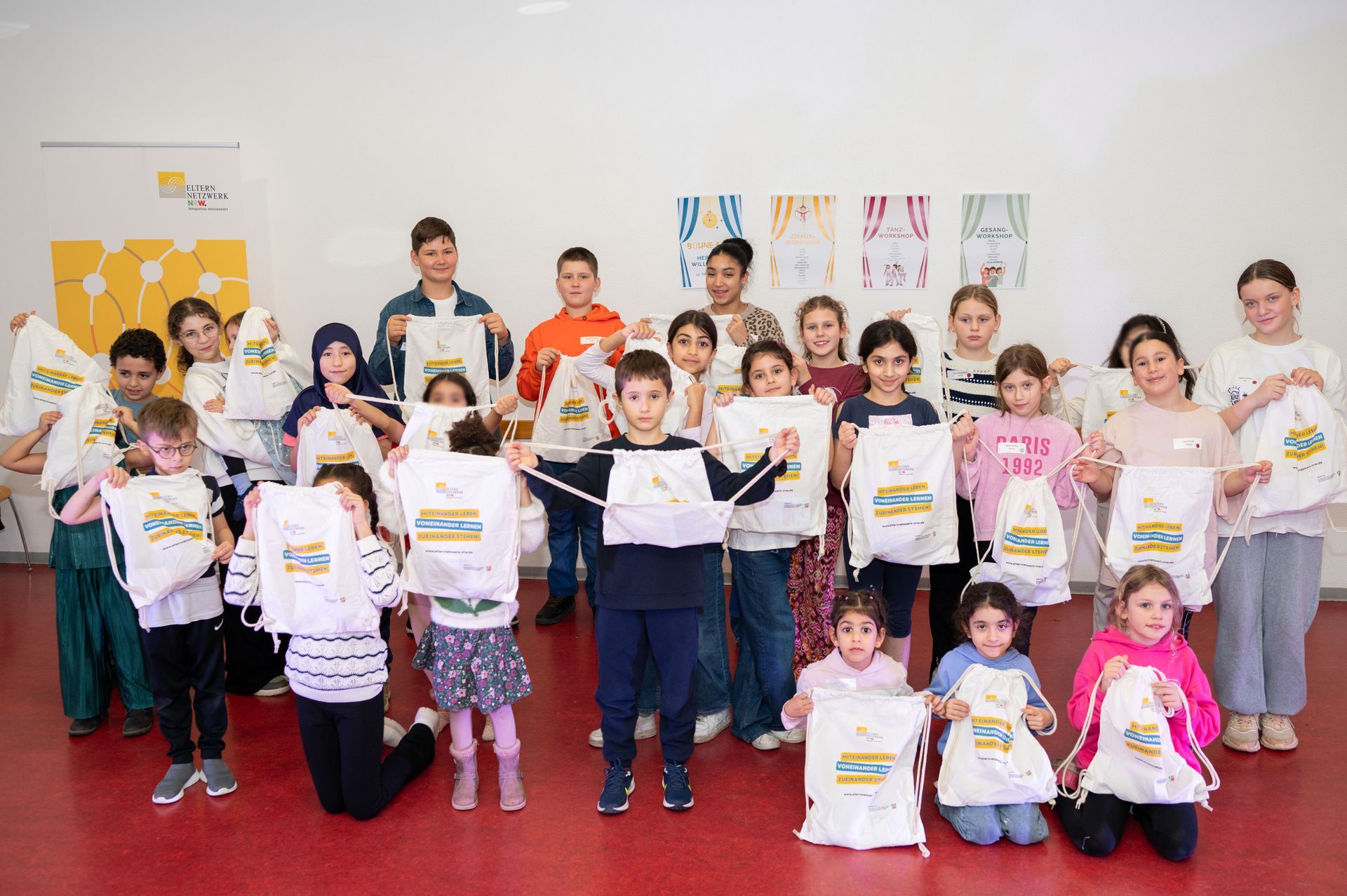 Gruppenbild aller Kinder der Veranstaltung. Sie halten ihre Jutebeutel vom Elternnetzwerk hoch.