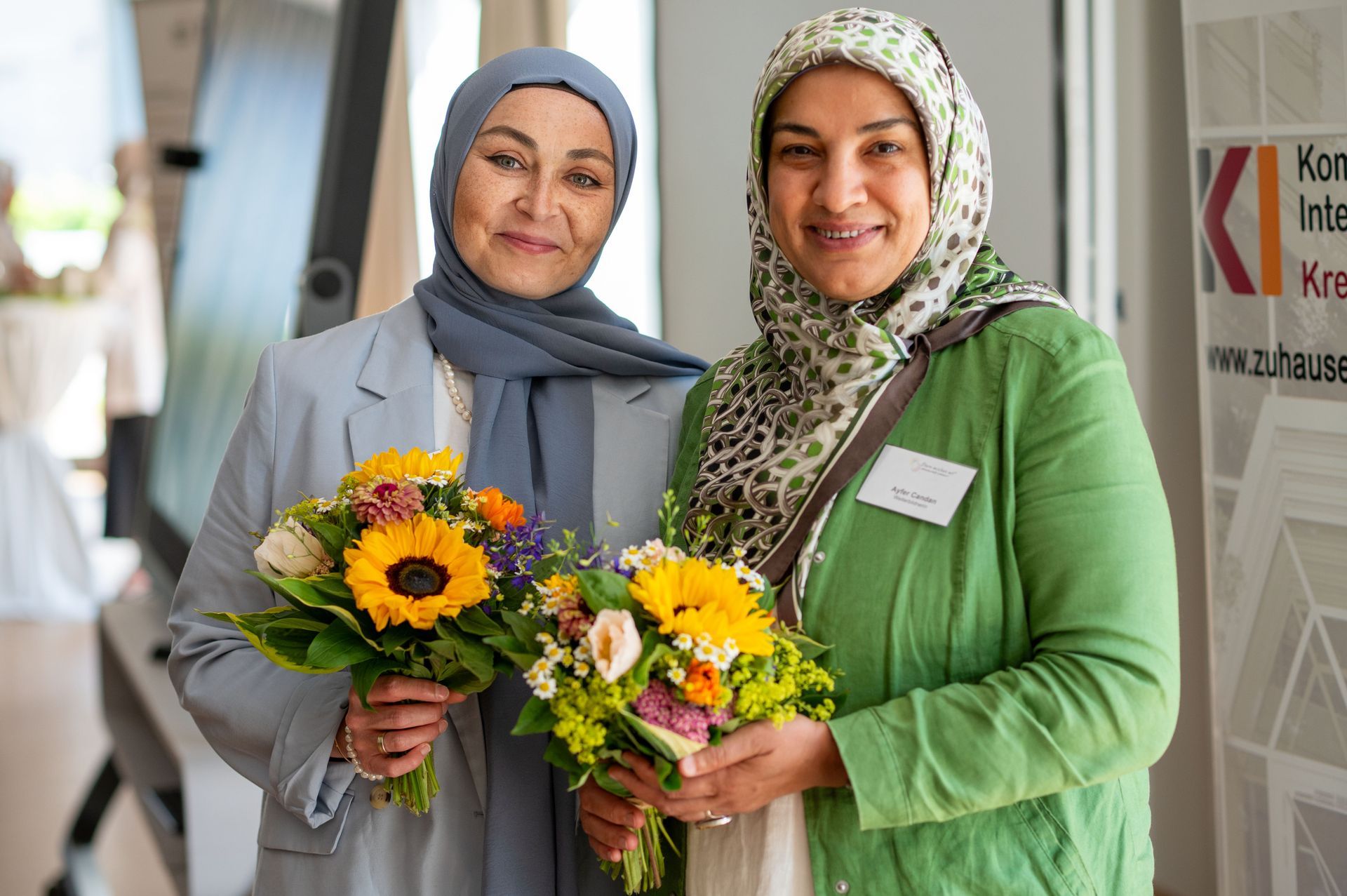 Zwei Frauen, u.a. Ayfer Candan, bei der Zertifizierungsfeier von Eltern-Moderator*innen lachen in die Kamera