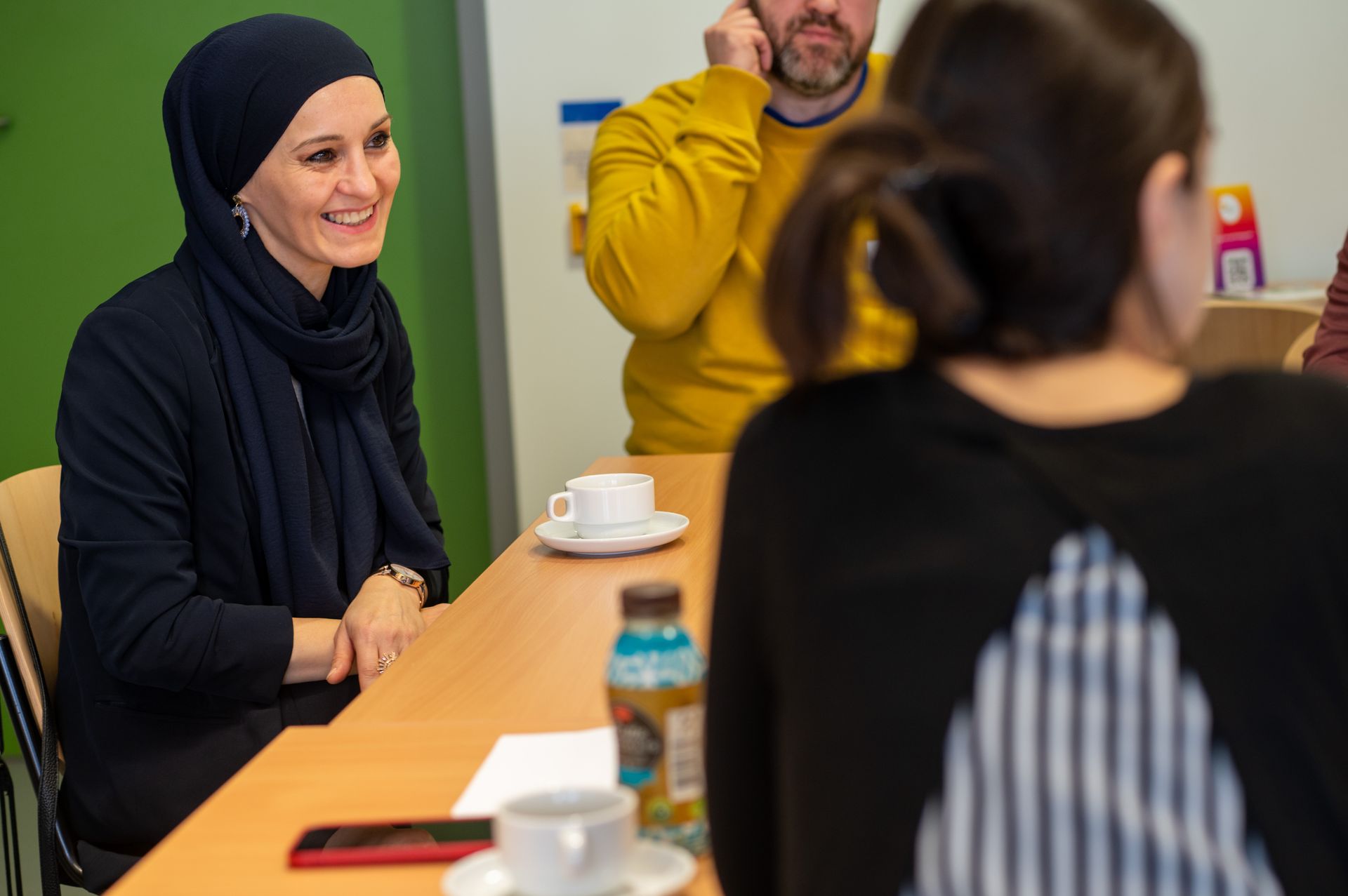 Eine Frau sitzt am Gruppentisch und lacht fröhlich. Fachtagung zur