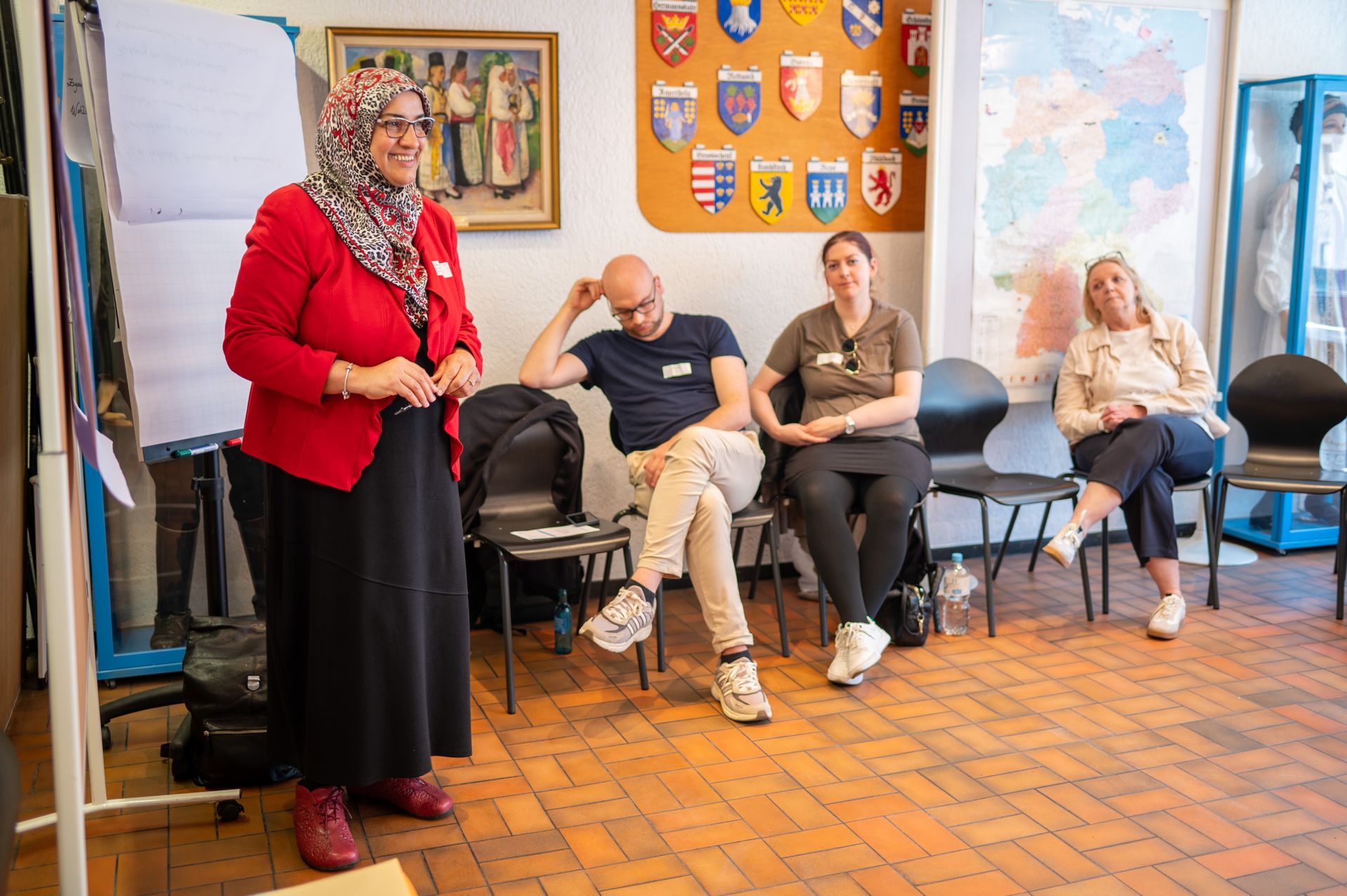 Workshop, links die Referentin vor einer Flipchart, rechts drei Teilnehmende im Stuhlkreis