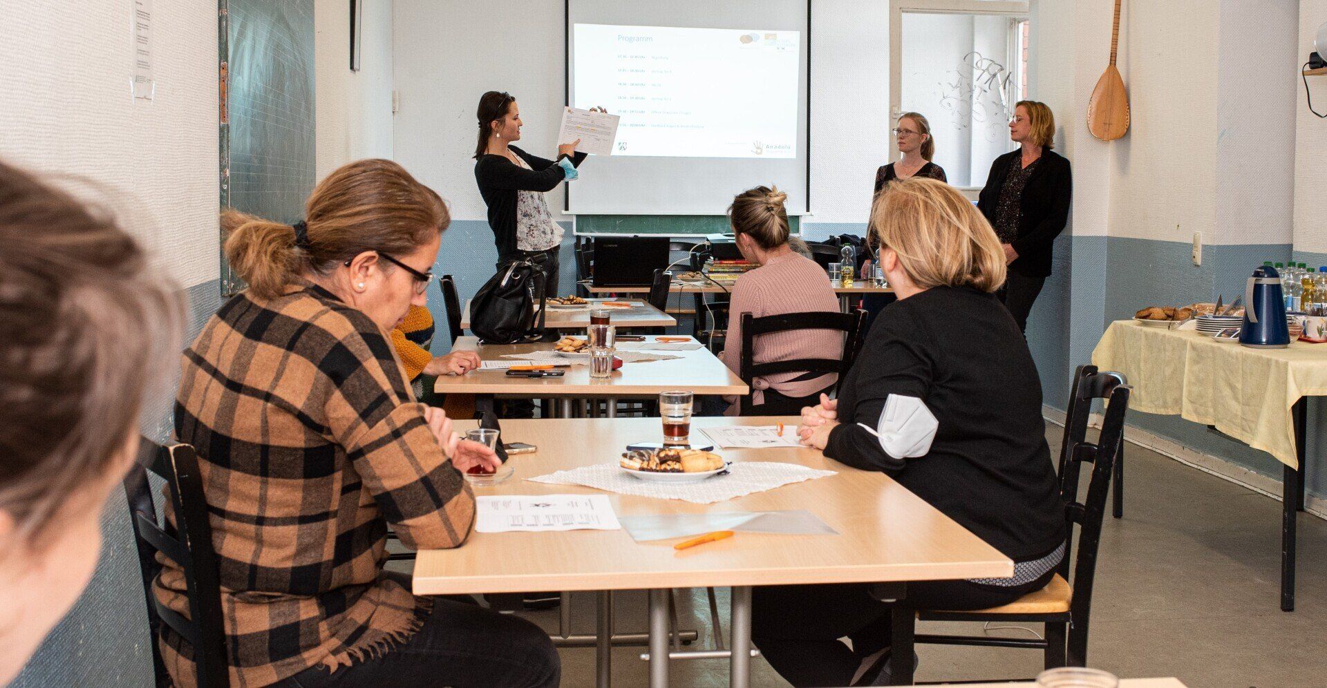 Eva Cynkar, Elternnetzwerk NRW, präsentiert beim Projekt Elterngespräche. Mehrere Teilnehmerinnen sitzen an Tischen verteilt